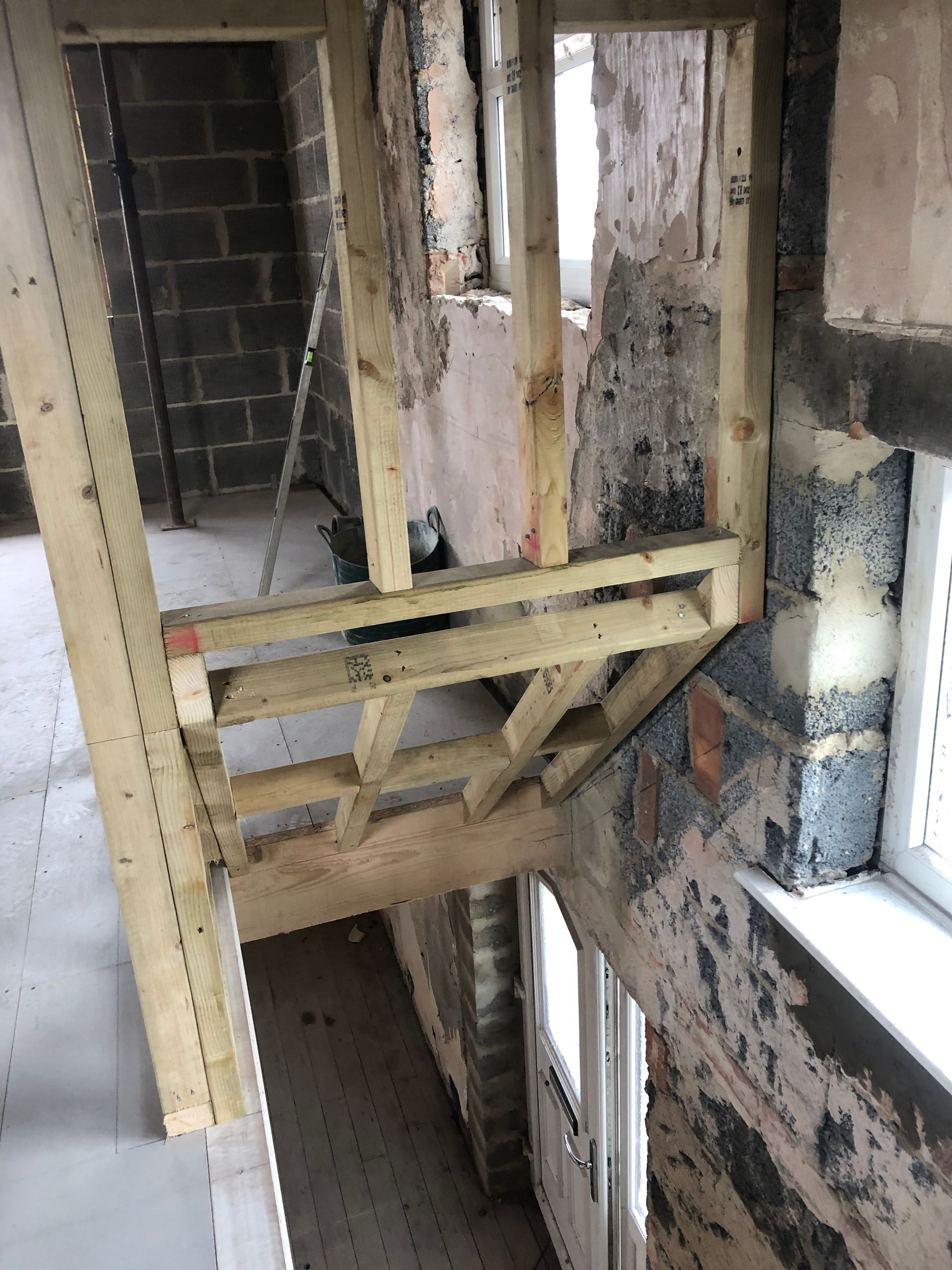 Construction site interior with wooden framework around a doorway and stairway.