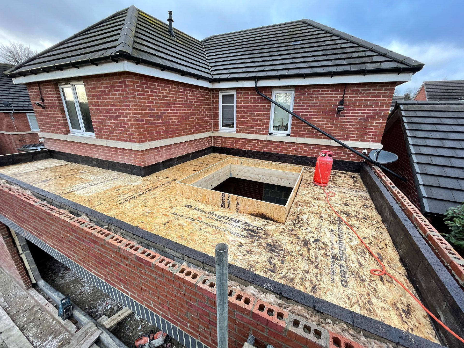 Brick building with a flat roof under construction; opening for skylight.