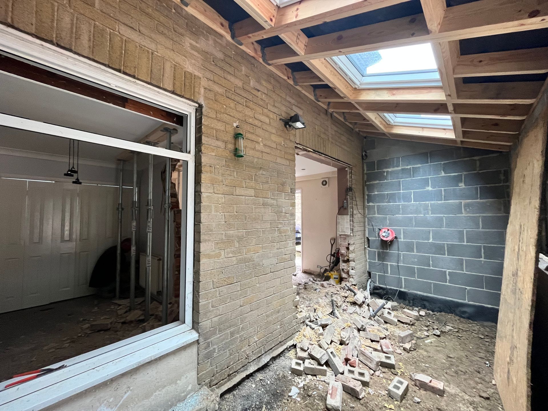 Renovation in progress; brick wall, concrete blocks, exposed ceiling beams, debris on floor.