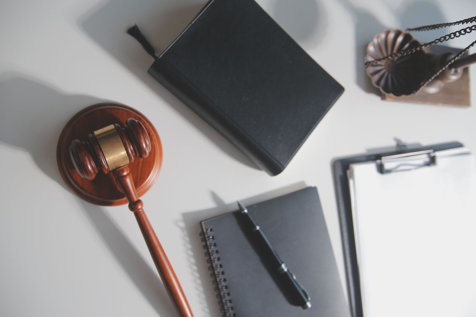 A judge 's gavel , a notebook , a pen , and a bible are on a table.