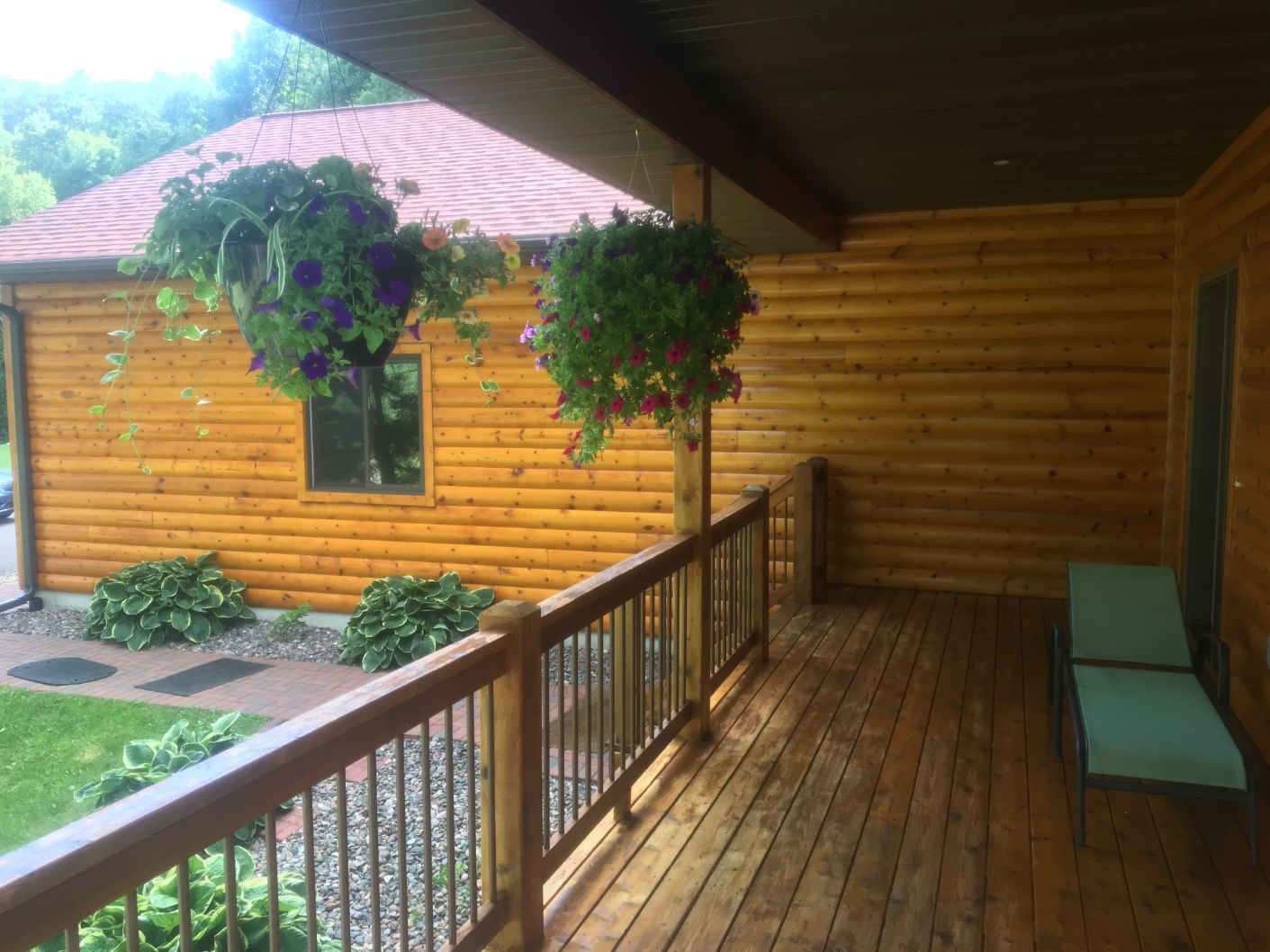 Wooden porch with hanging flower baskets and a lounge chair.