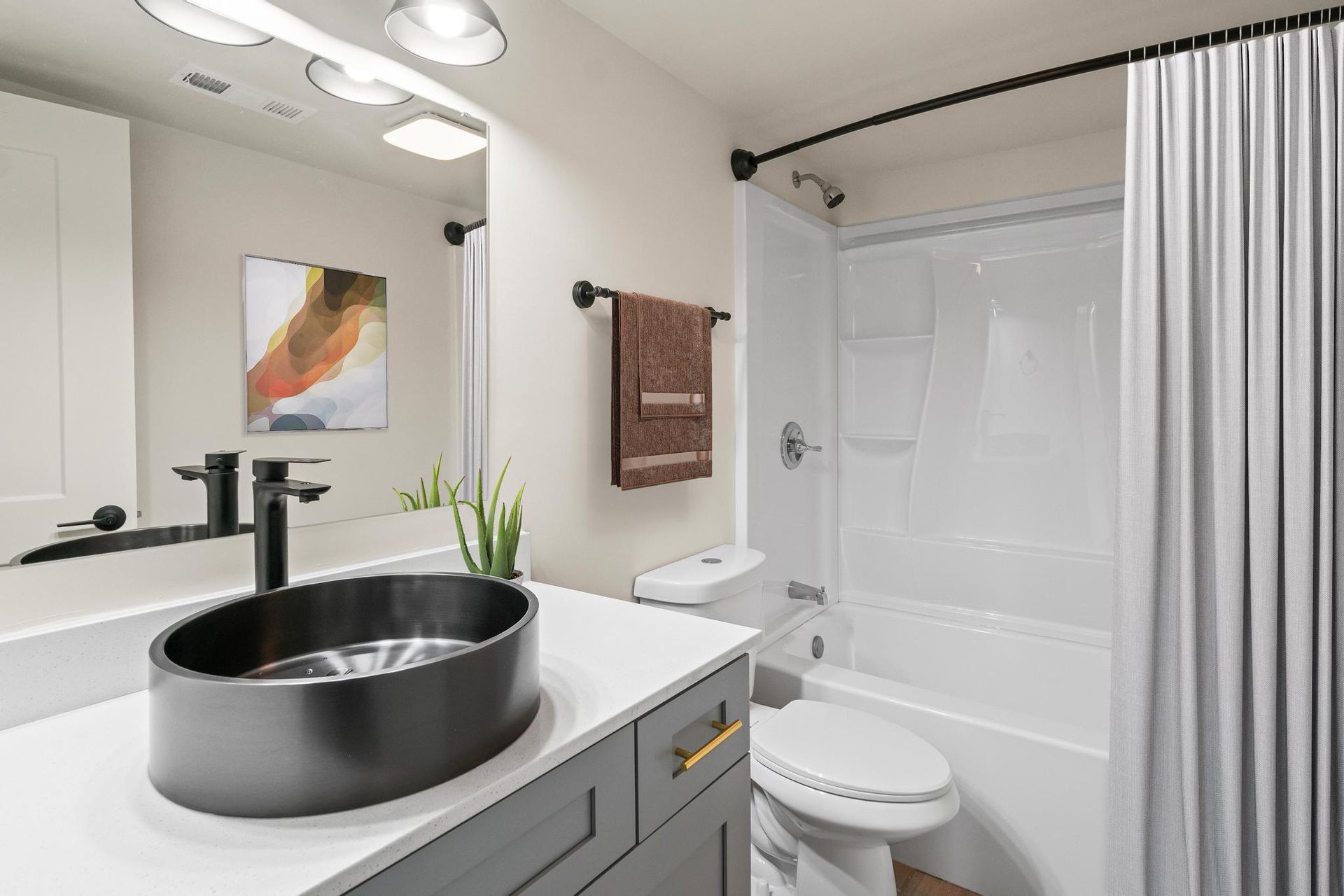 A bathroom with a sink , toilet , shower and mirror.