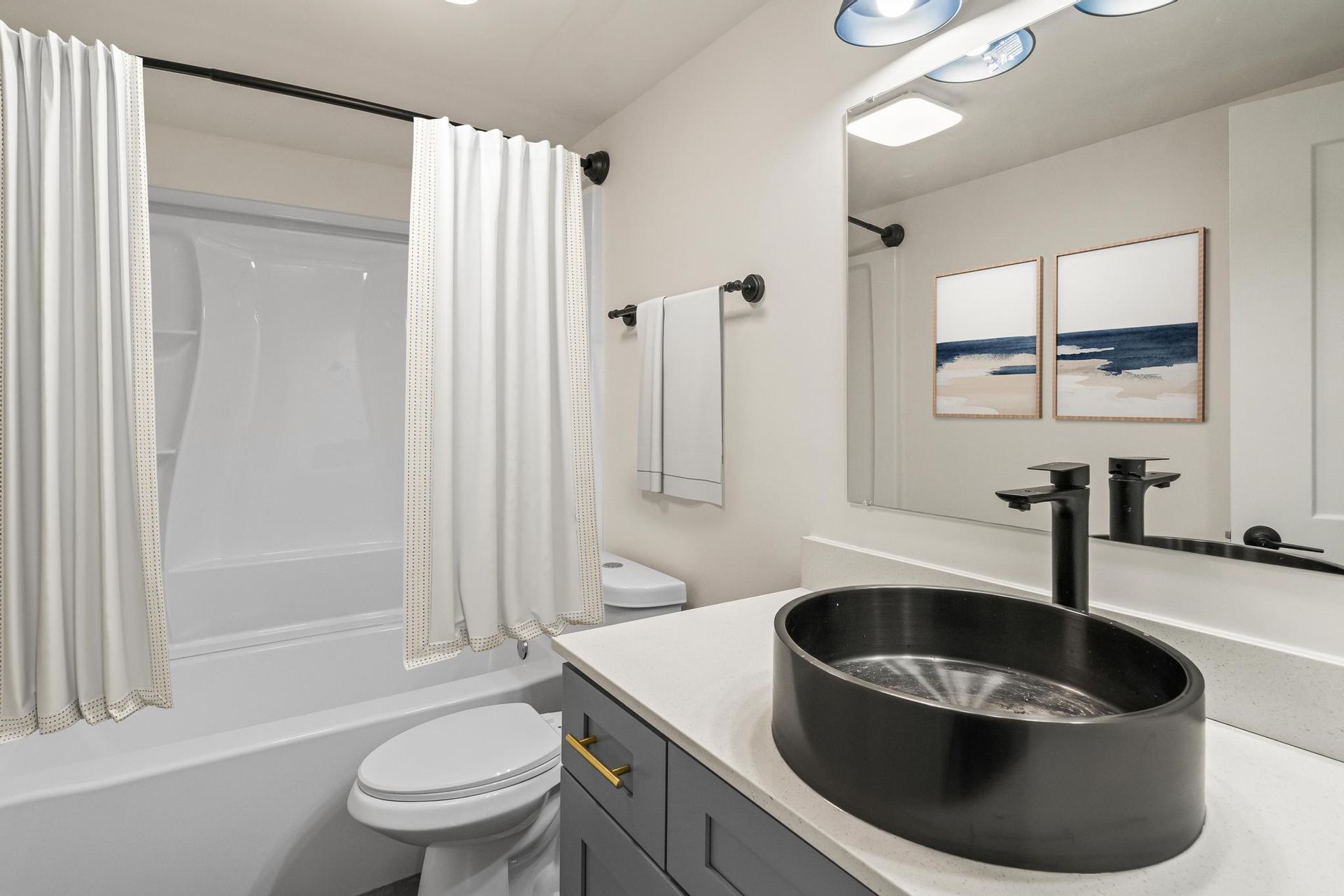A bathroom with a sink , toilet , bathtub and mirror.