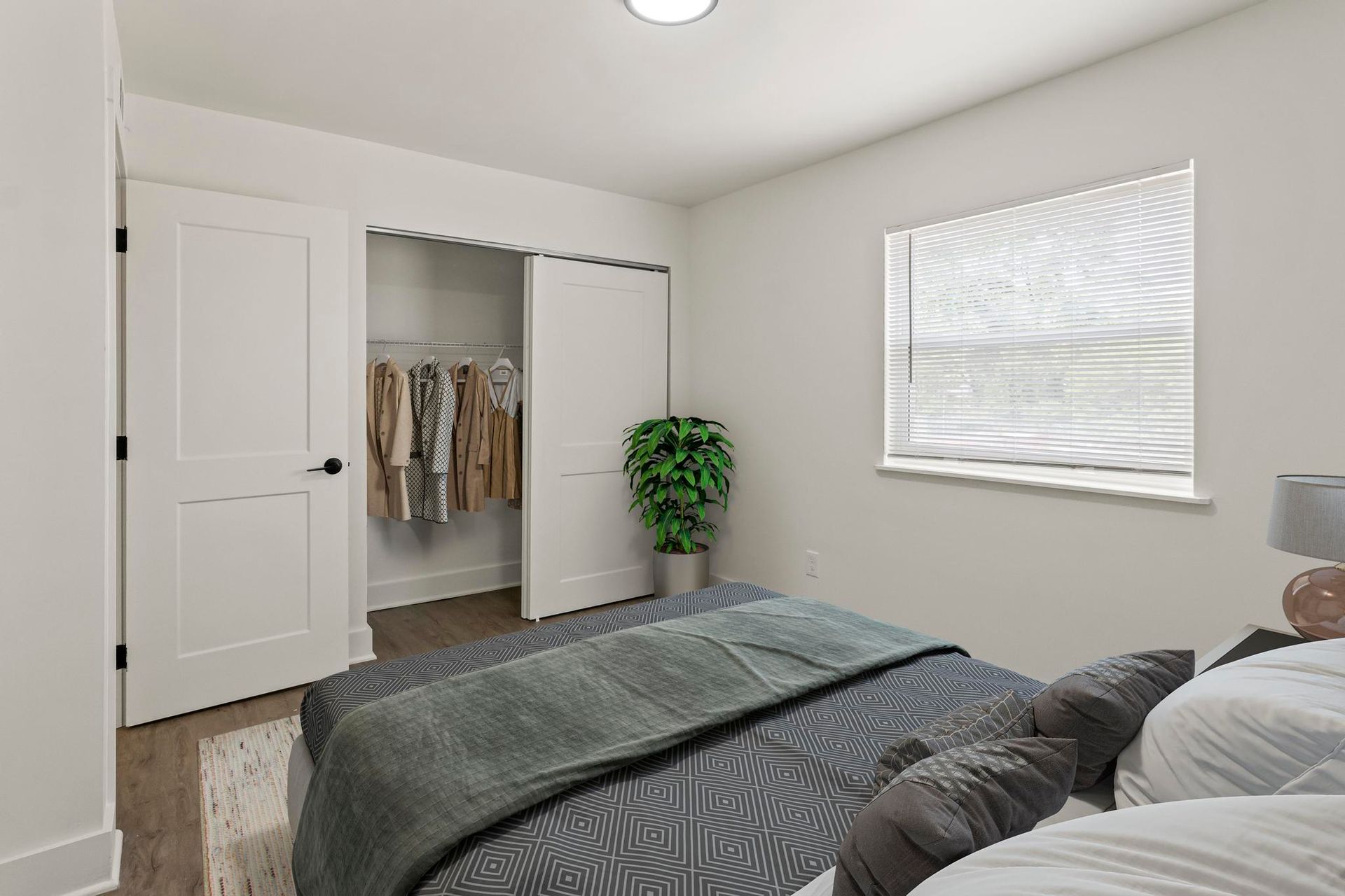 A bedroom with a bed , closet and window.