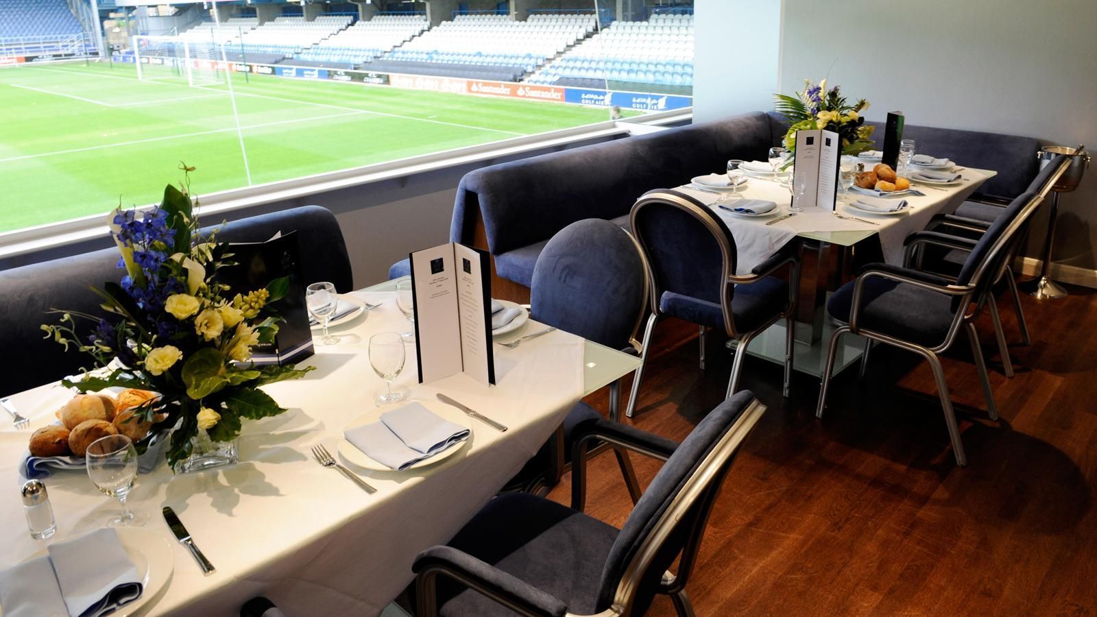 Dining tables set in a stadium suite overlooking the field