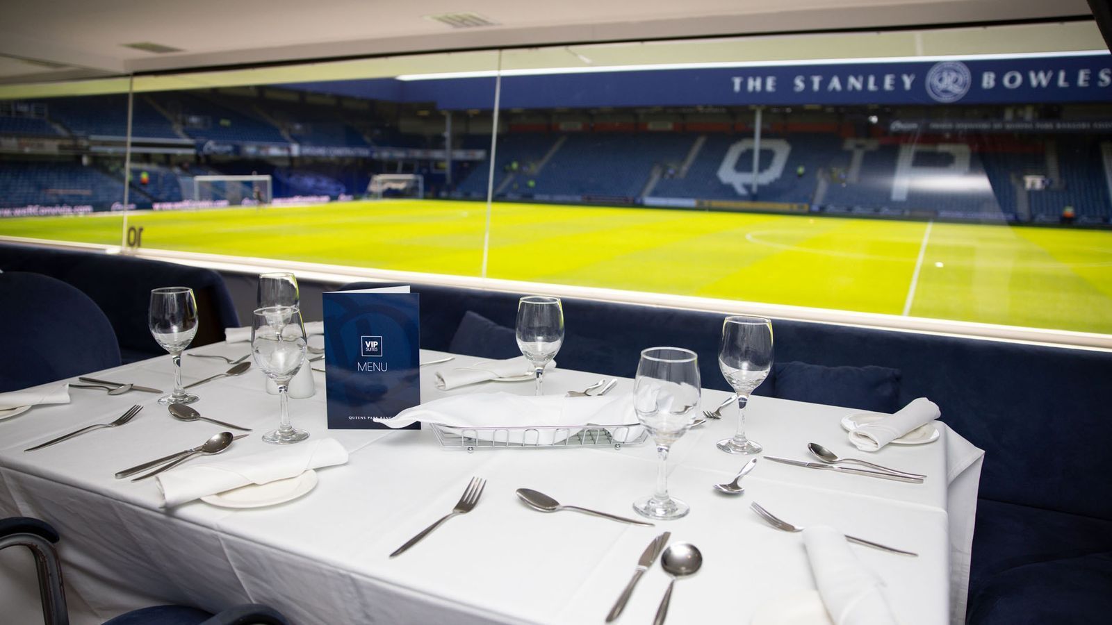 Set dining table overlooking a football stadium field with blue seats and yellow sidelines