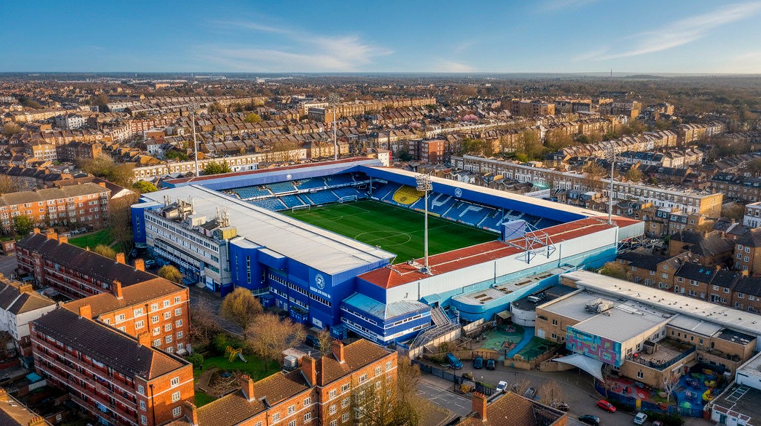 Aerial view of a blue-and-white soccer stadium in a city neighborhood at sunset