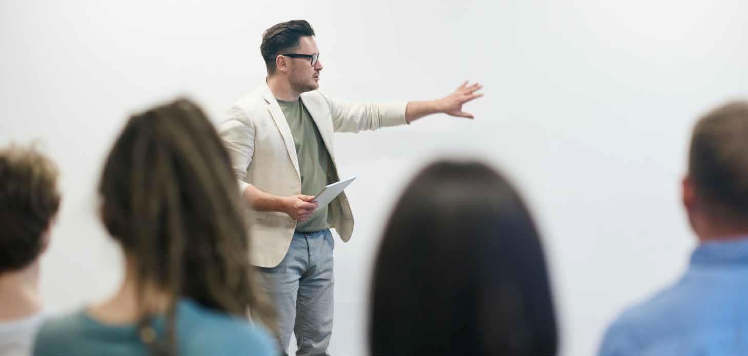 Presenter gesturing during a talk to an audience in a bright conference room