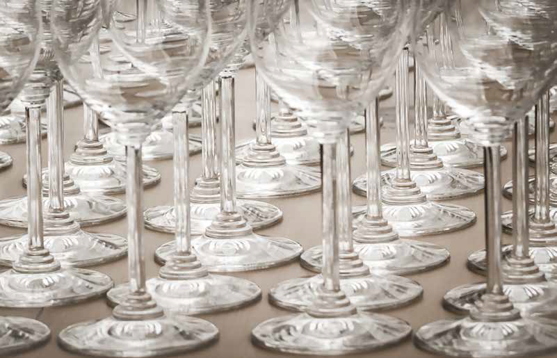 Rows of clear wine glasses and champagne flutes arranged closely on a table