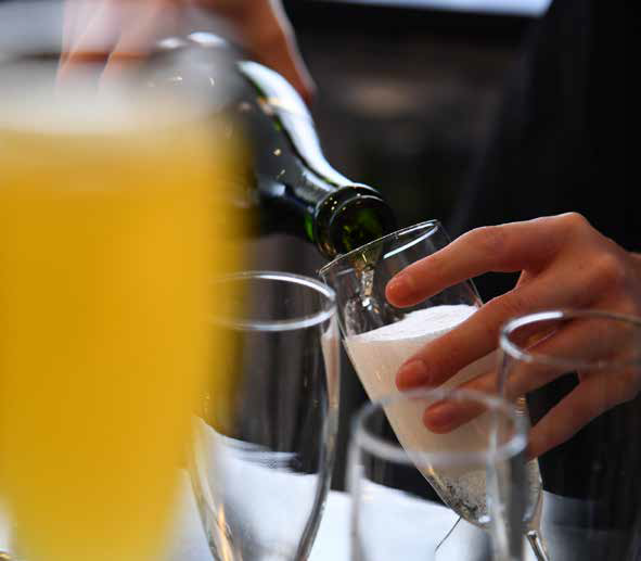 Hand pouring sparkling wine into a champagne flute at a formal event
