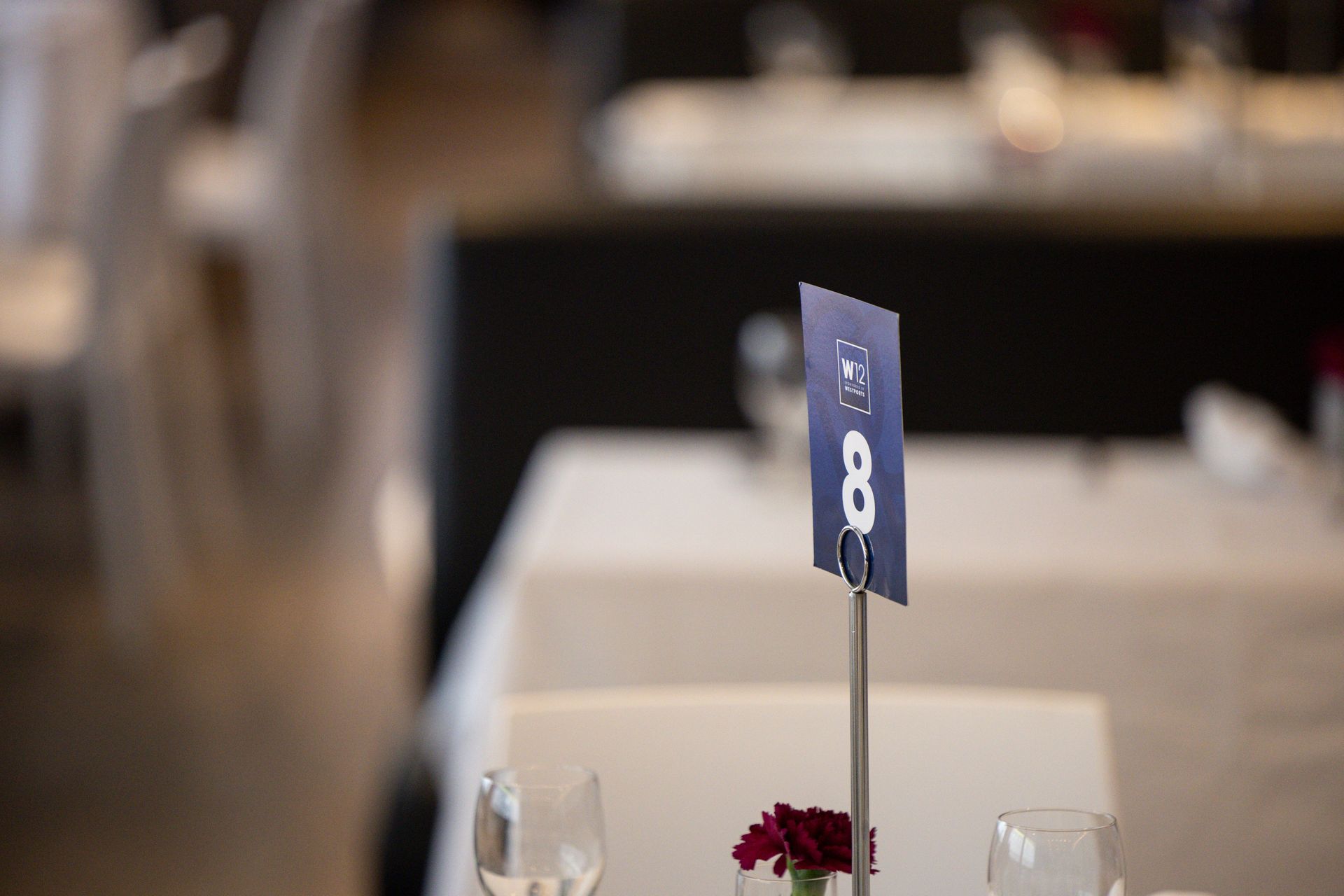 Table number 8 on a banquet table with white linens and small floral decor, blurred background