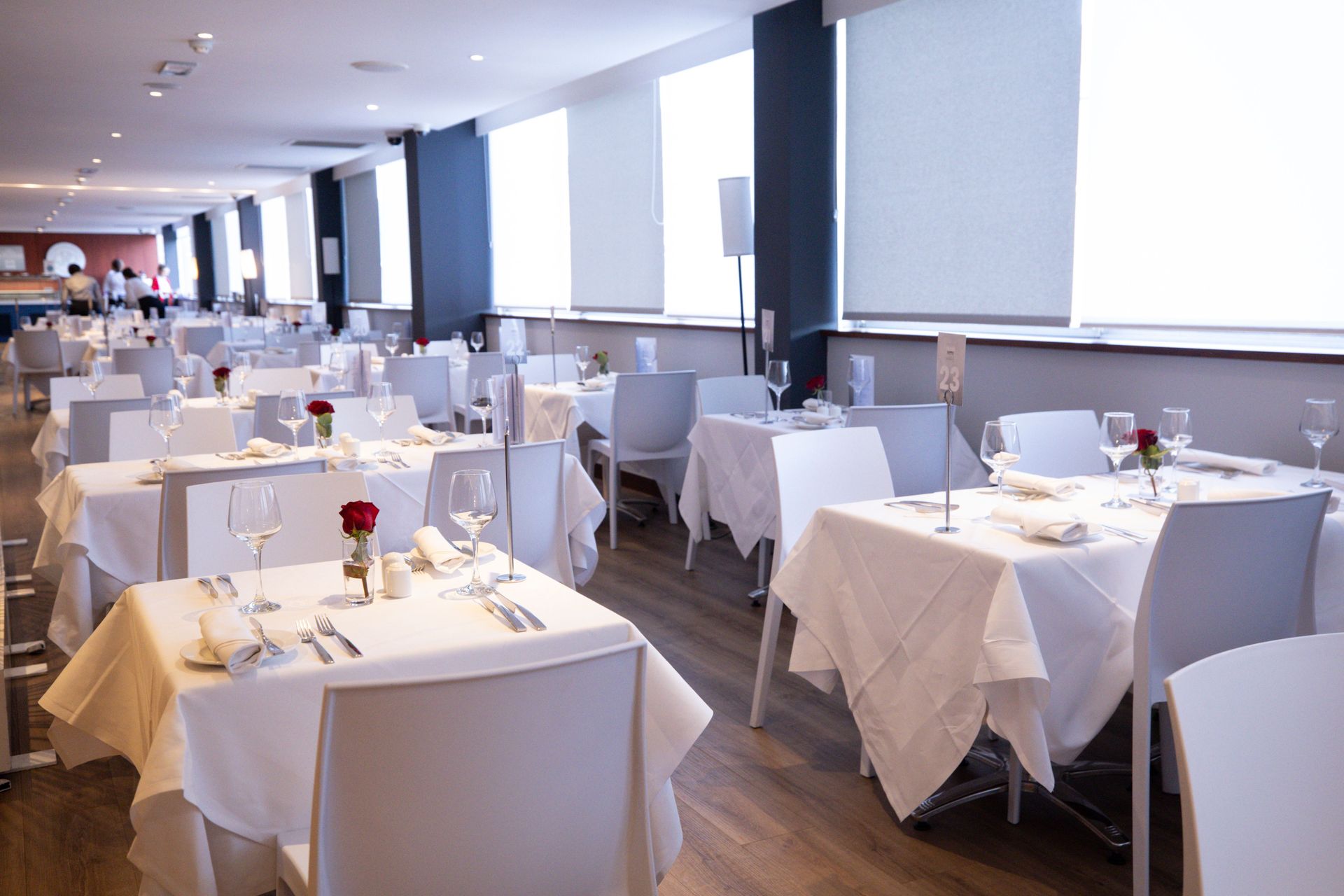 Bright modern restaurant dining room with white tablecloths and large windows