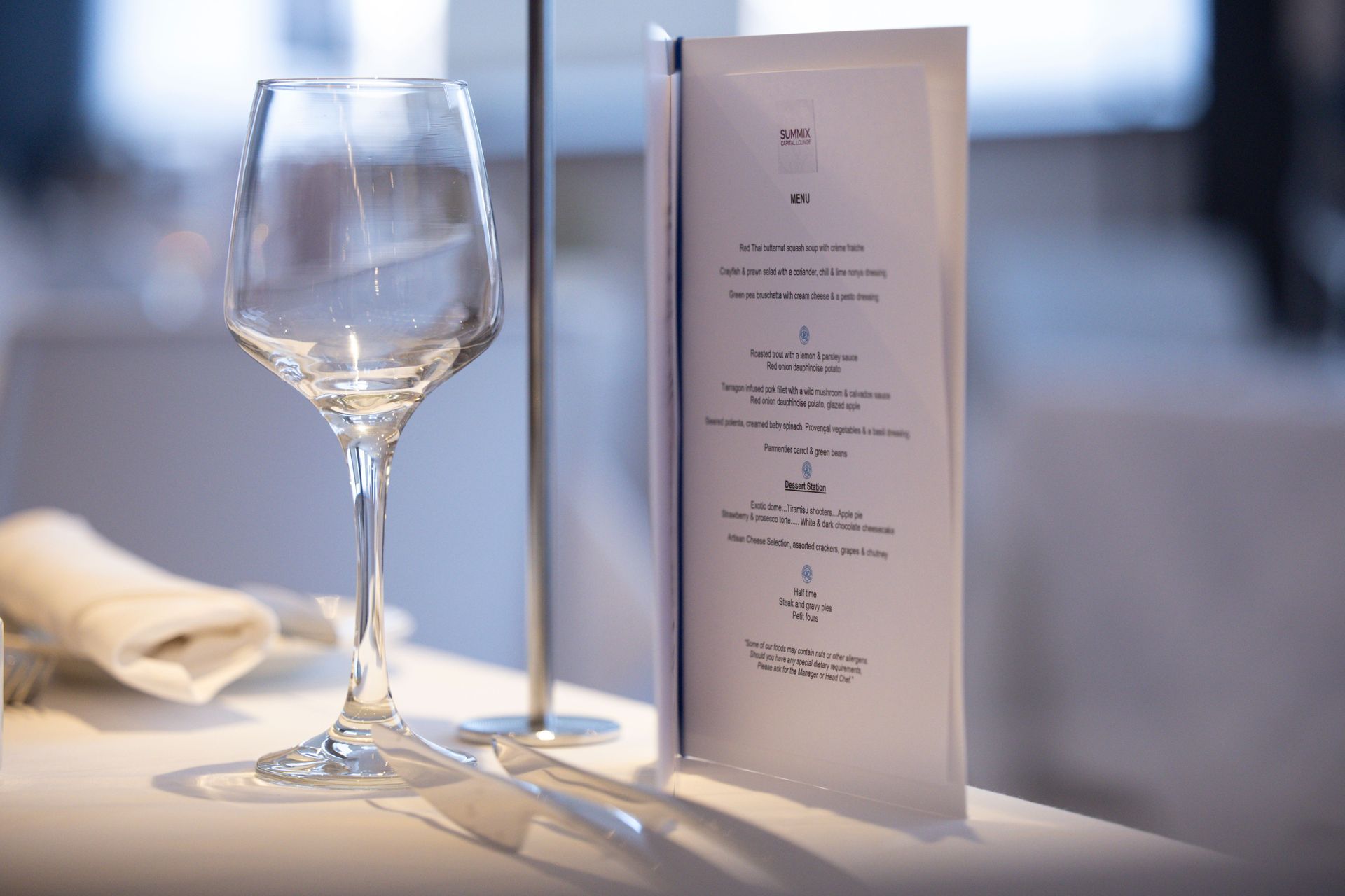 Wine glass beside a folded menu on a softly lit dining table