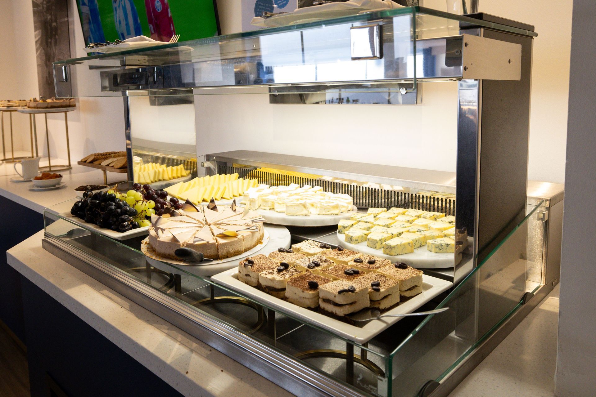 Dessert buffet display with assorted pastries and cakes on trays behind glass