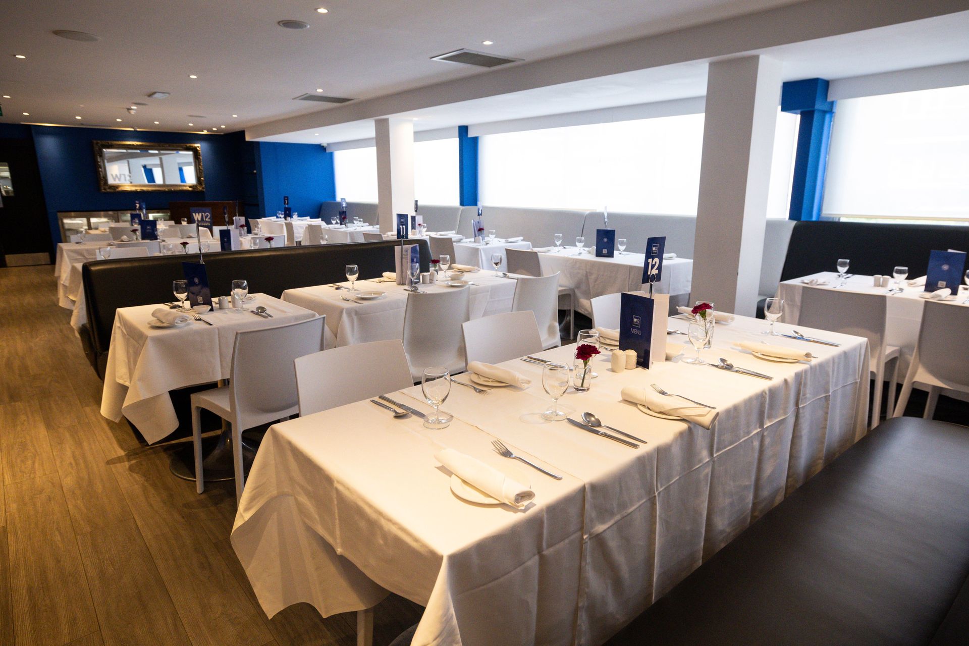 Elegant restaurant dining room with white tablecloths, neatly set tables, and large windows along the wall