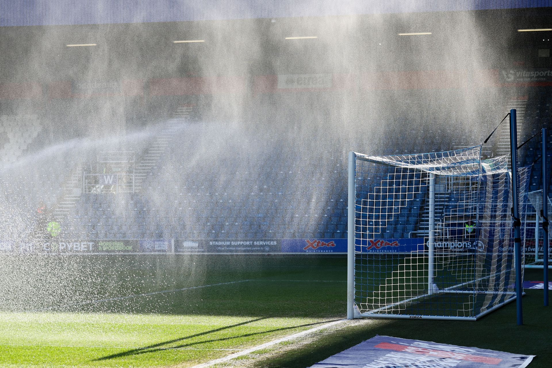 Water spraying over a soccer goal on a sunlit field