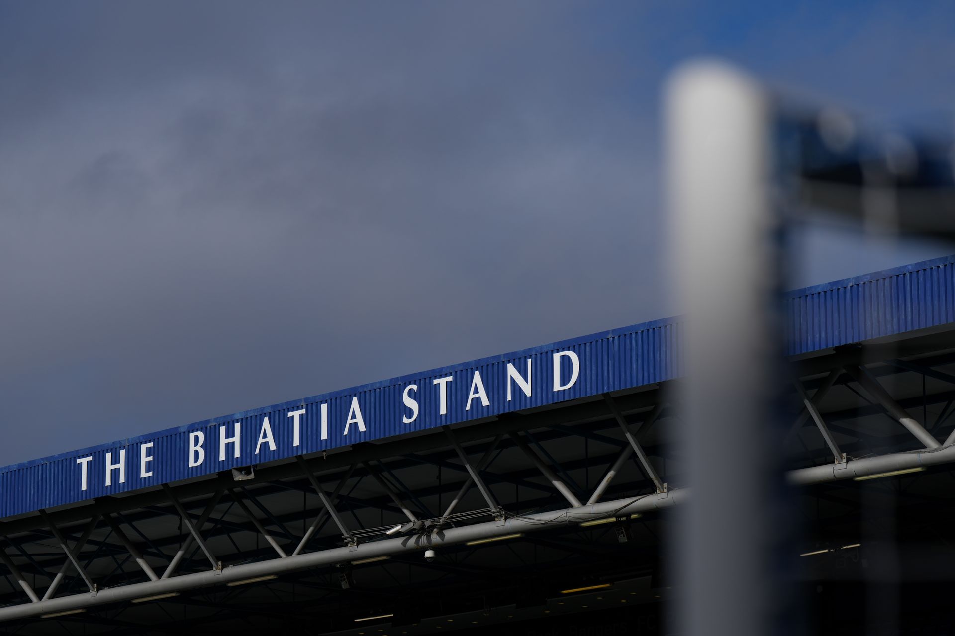 The Bhatia Stand sign on a stadium roof against a cloudy sky