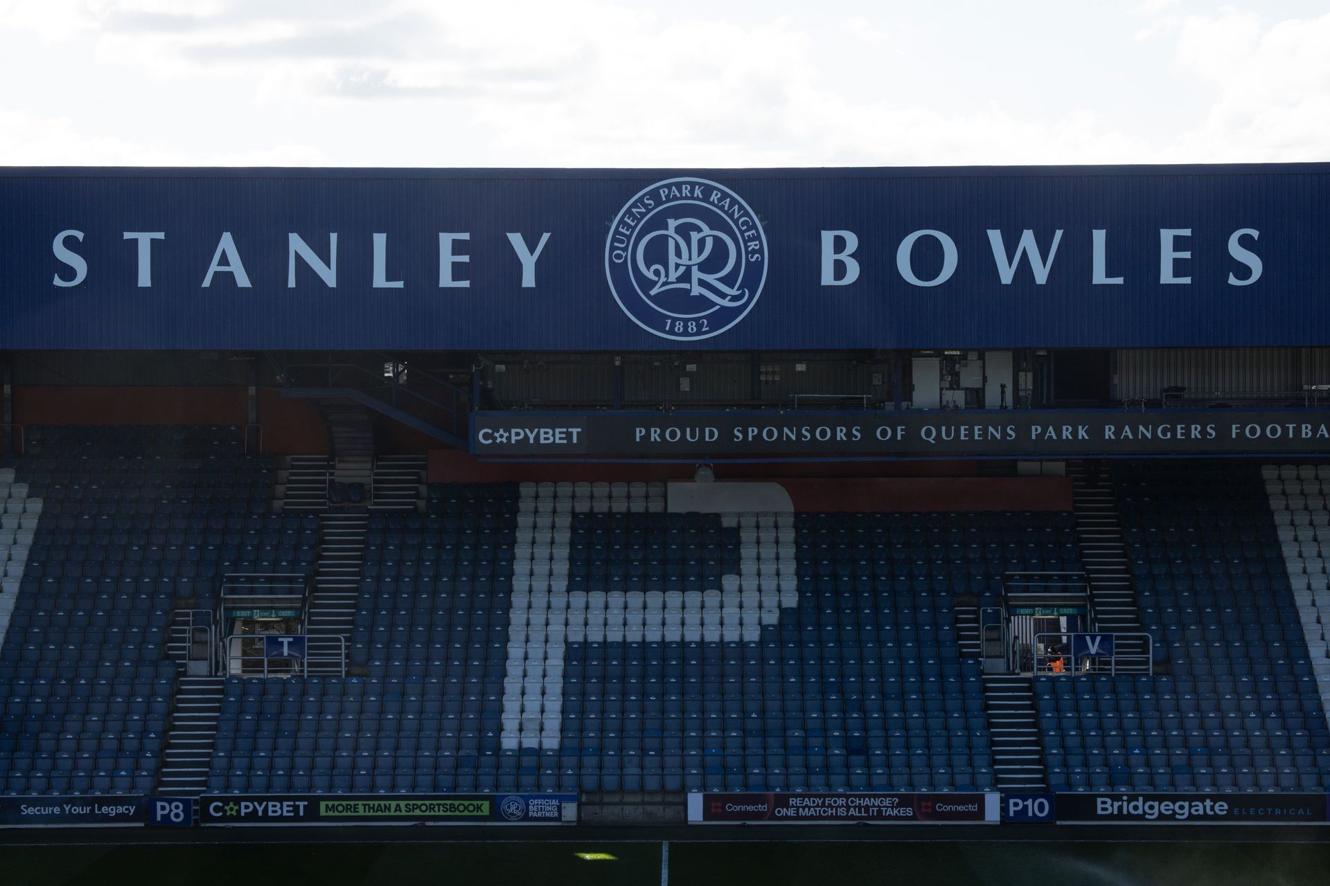 Stanley Bowles stadium stand with blue seats forming a large white “P” and club crest banner above