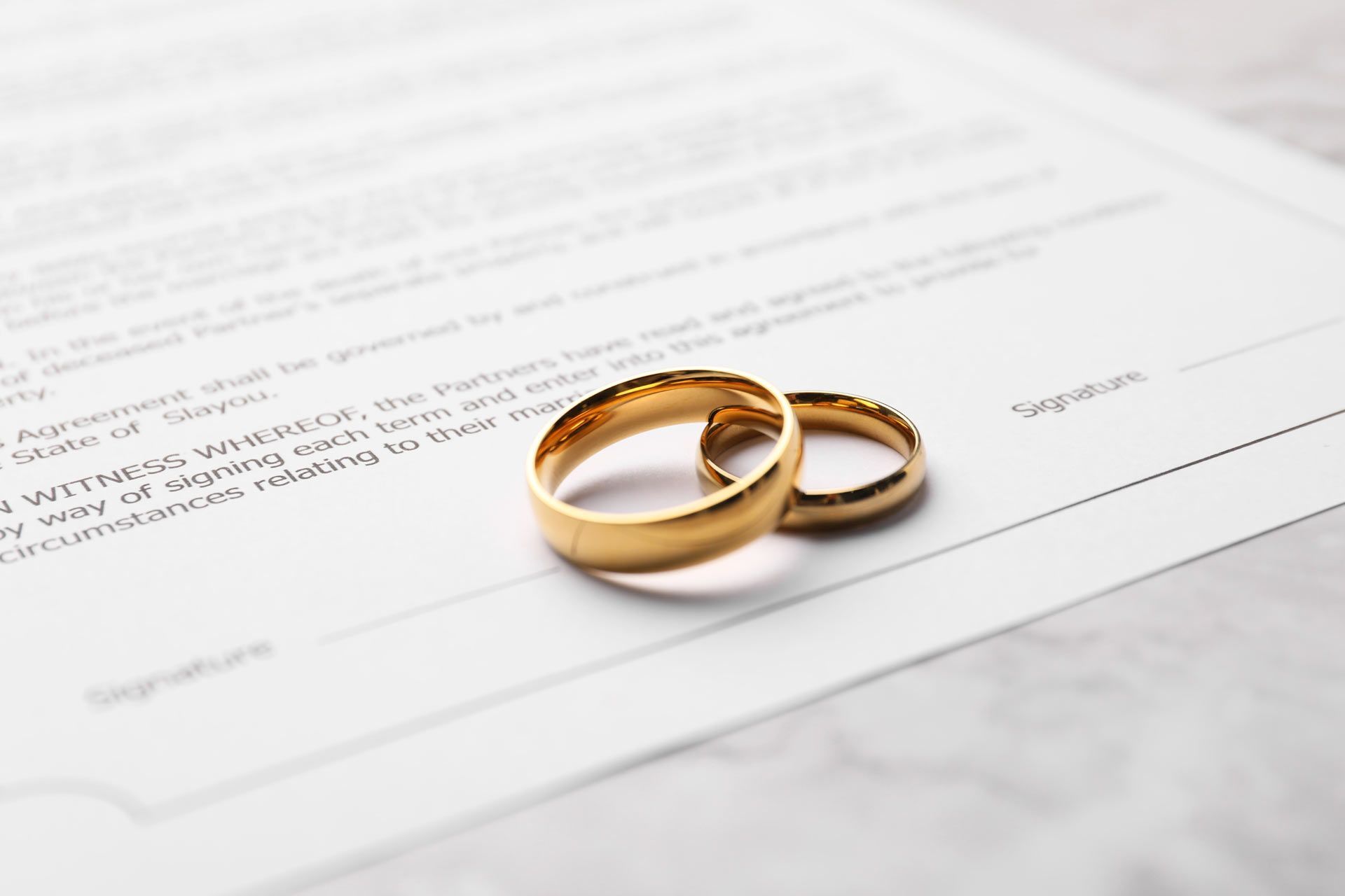 Two gold wedding rings rest on a divorce agreement.