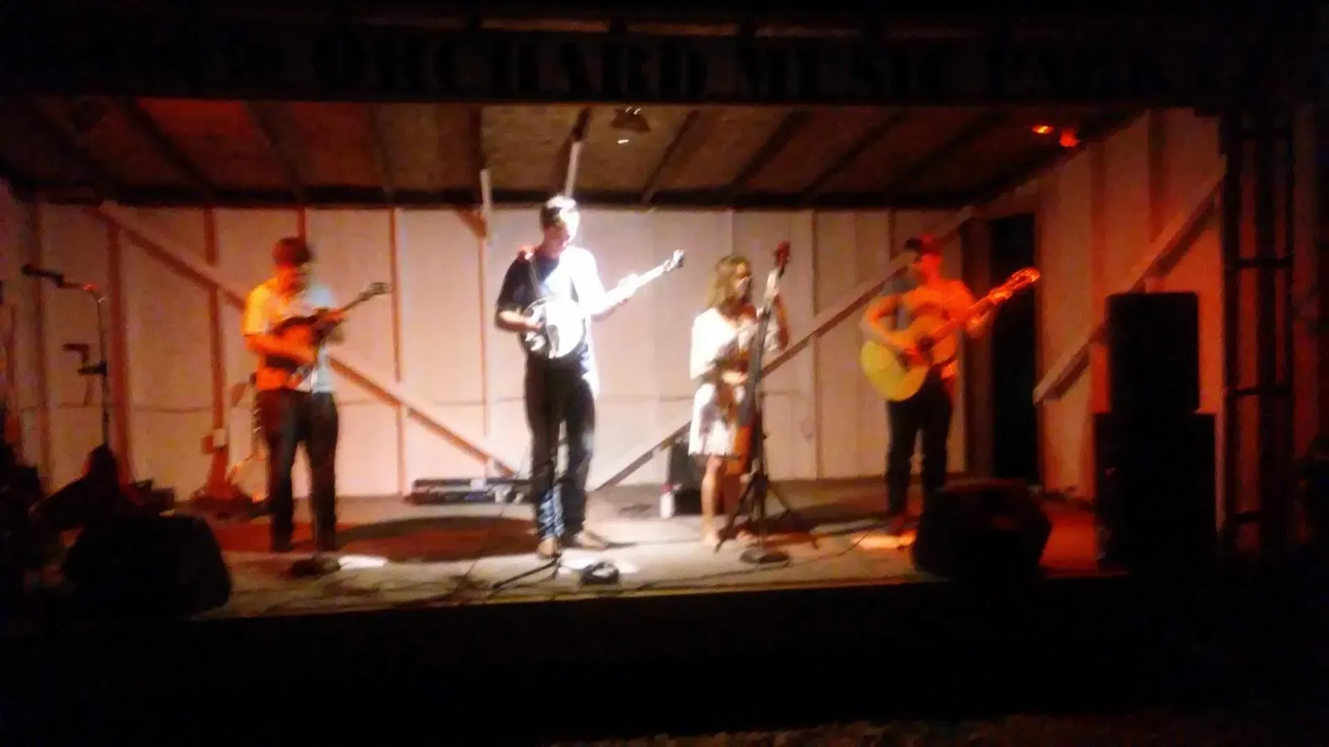 A group of people are playing guitars on a stage with a sign that says ' theatre ' on it