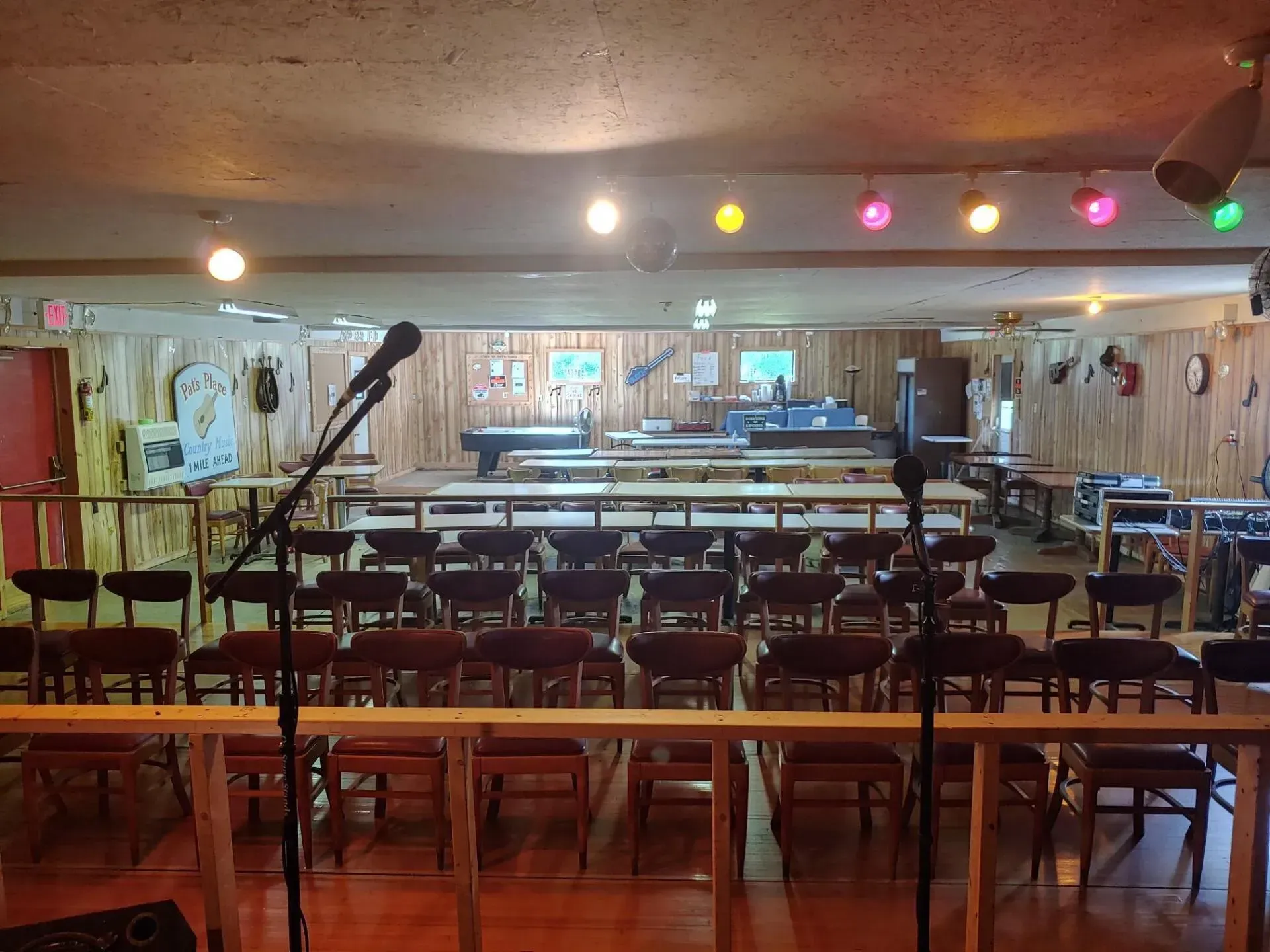 A large room with tables and chairs and a microphone on the stage