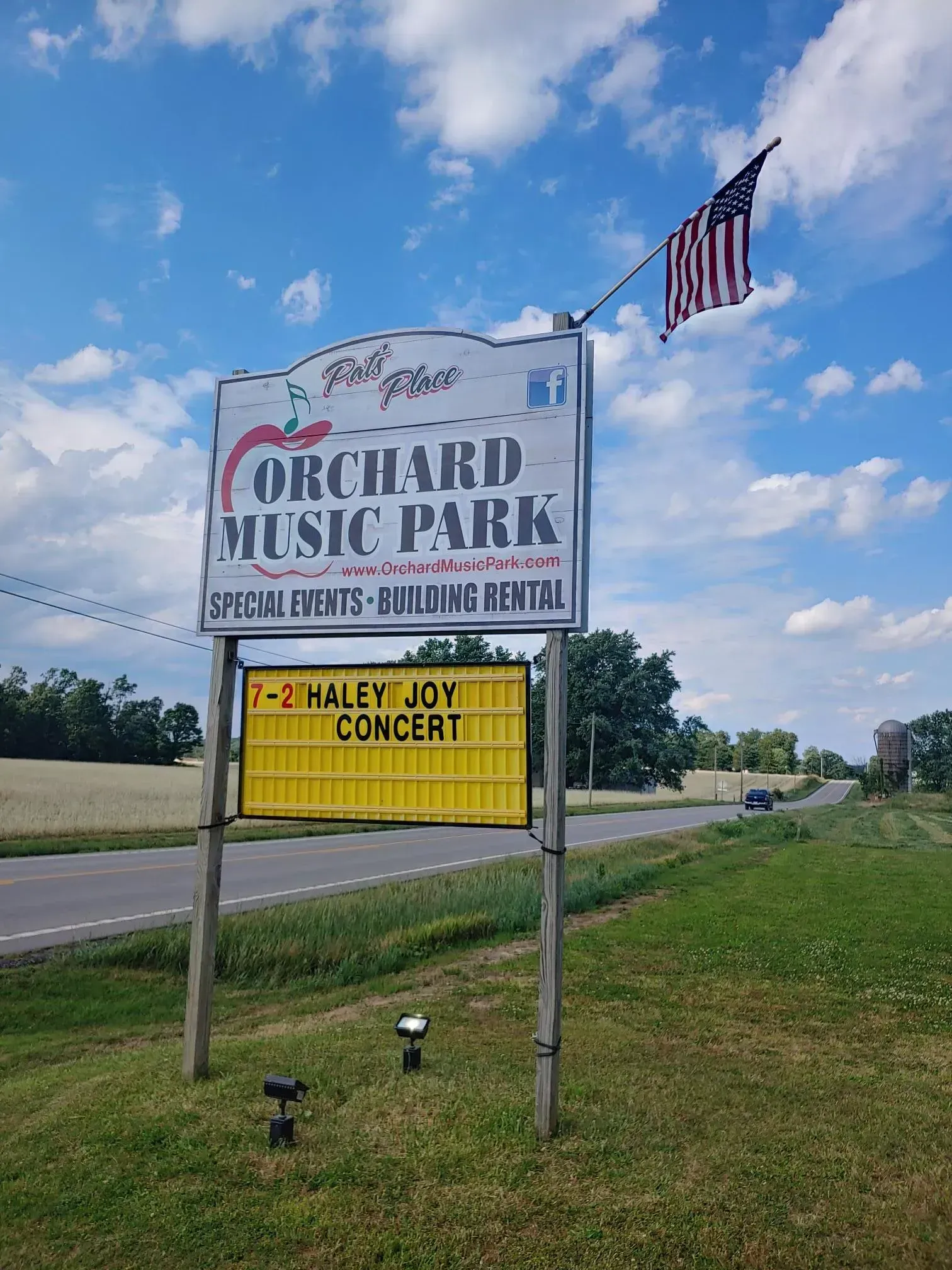 A sign for orchard music park is sitting on the side of the road.