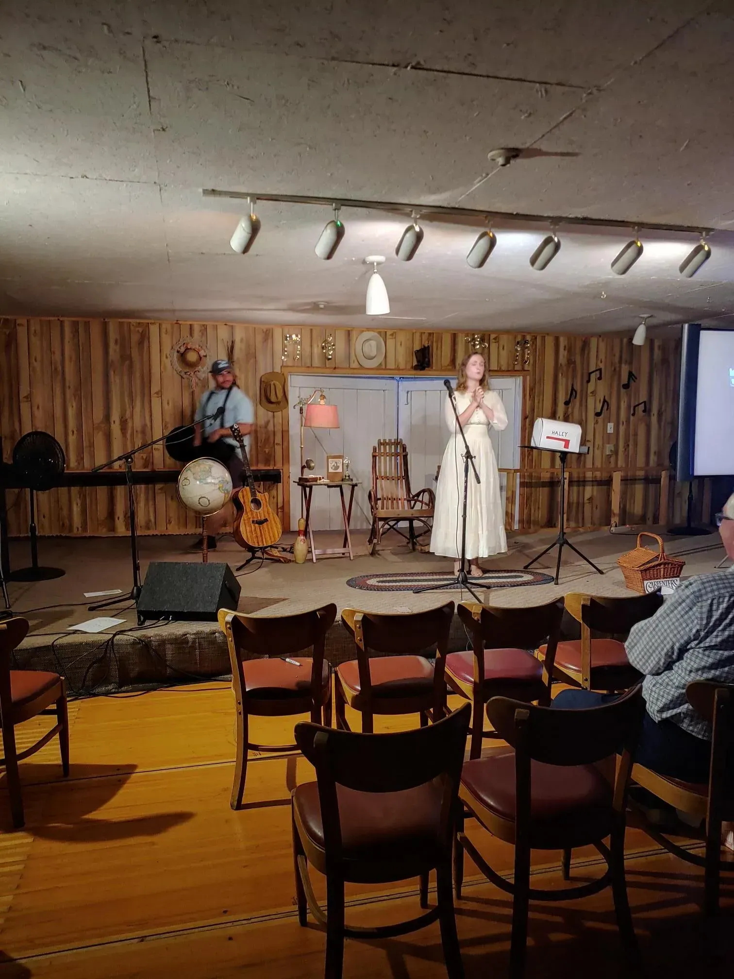 A woman is singing into a microphone in front of a group of people sitting in chairs.