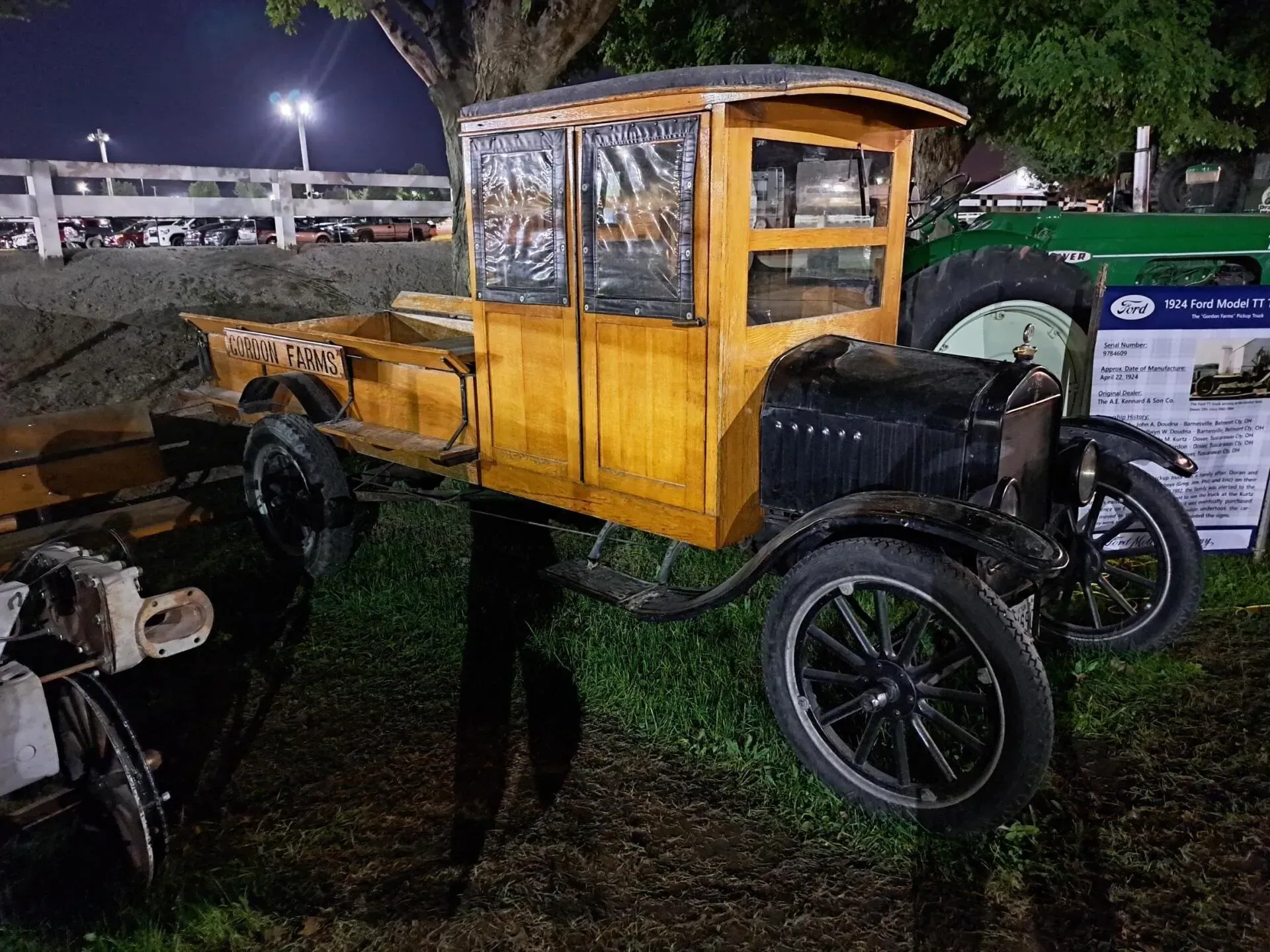 An old truck with a wooden bed is parked in the grass.