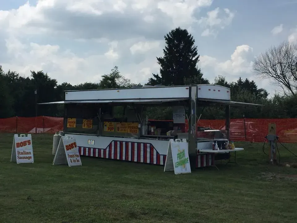 A food truck in a field with a sign that says donuts