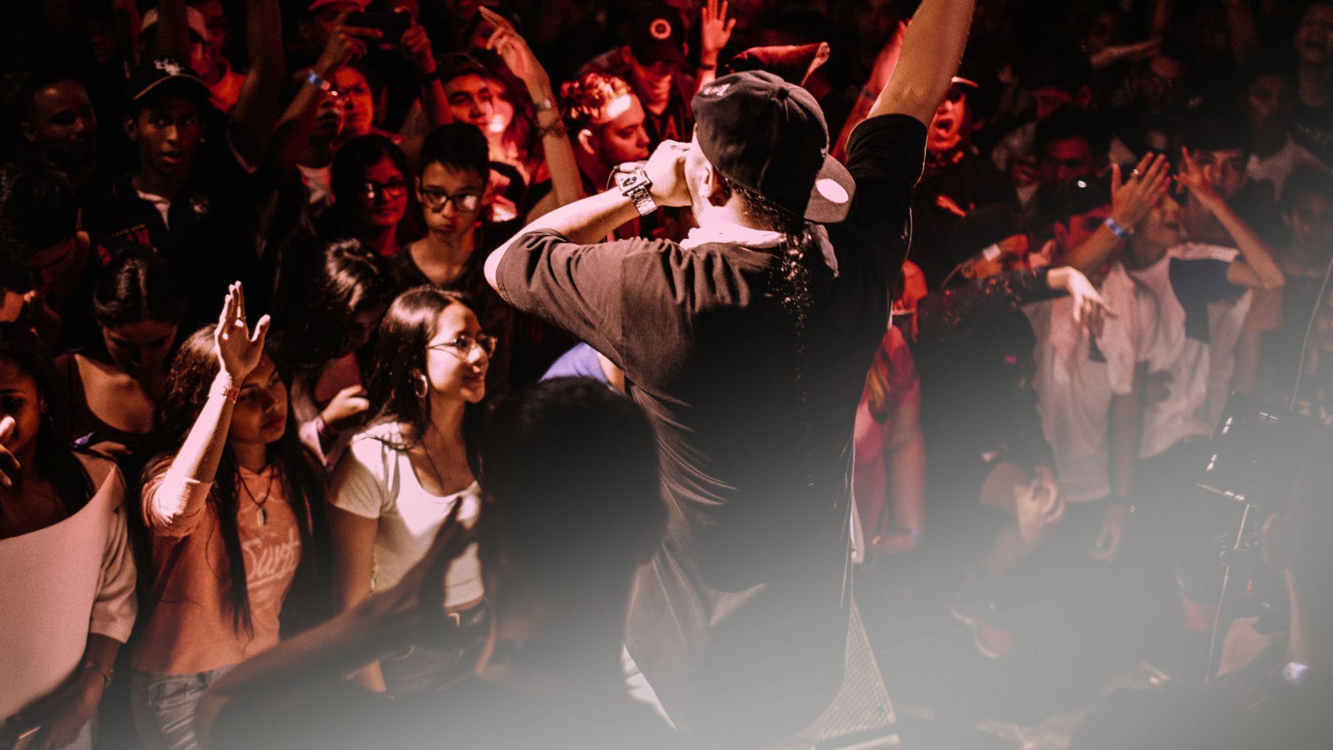 A man is standing in front of a crowd of people at a concert.
