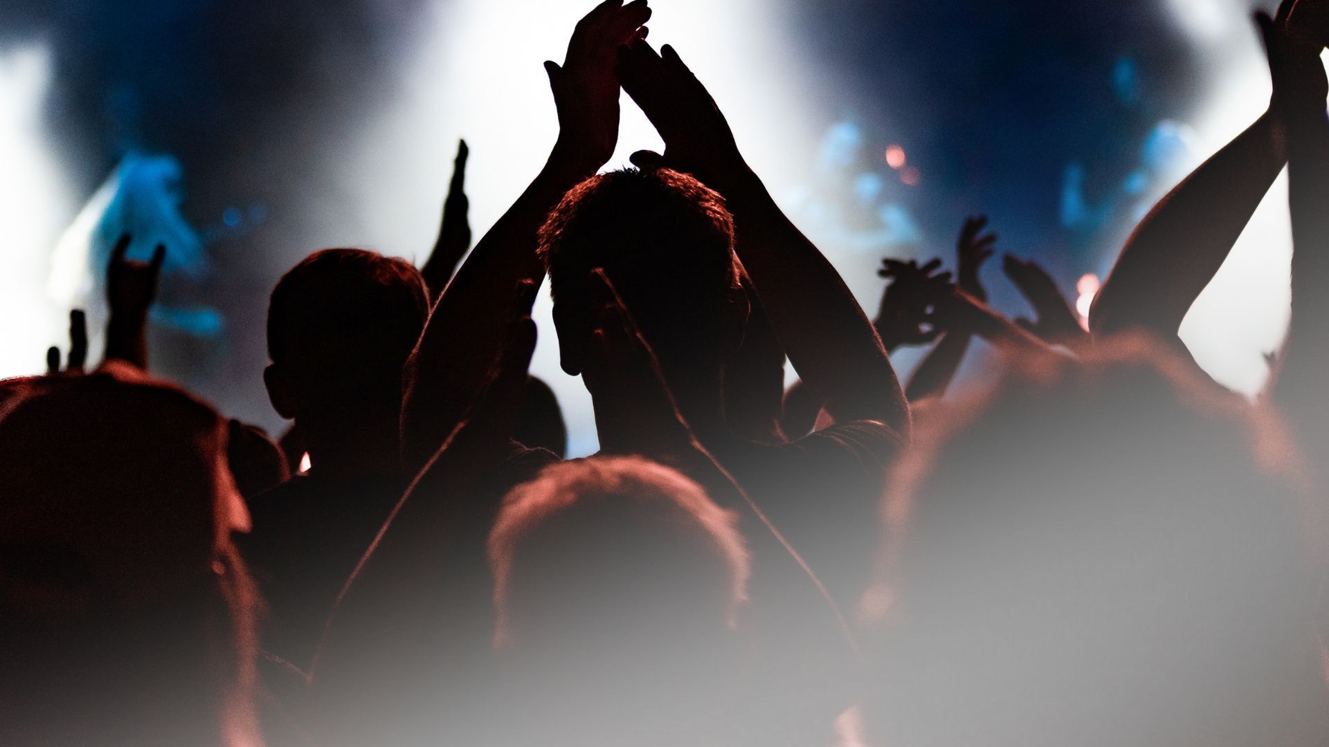 A crowd of people with their hands in the air at a concert