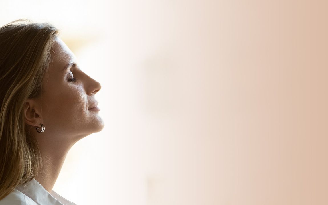 A woman is looking up at the sky with her eyes closed.