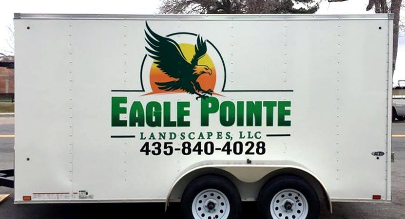 White trailer with green and orange Eagle Pointe Landscapes logo, contact number 435-840-4028.