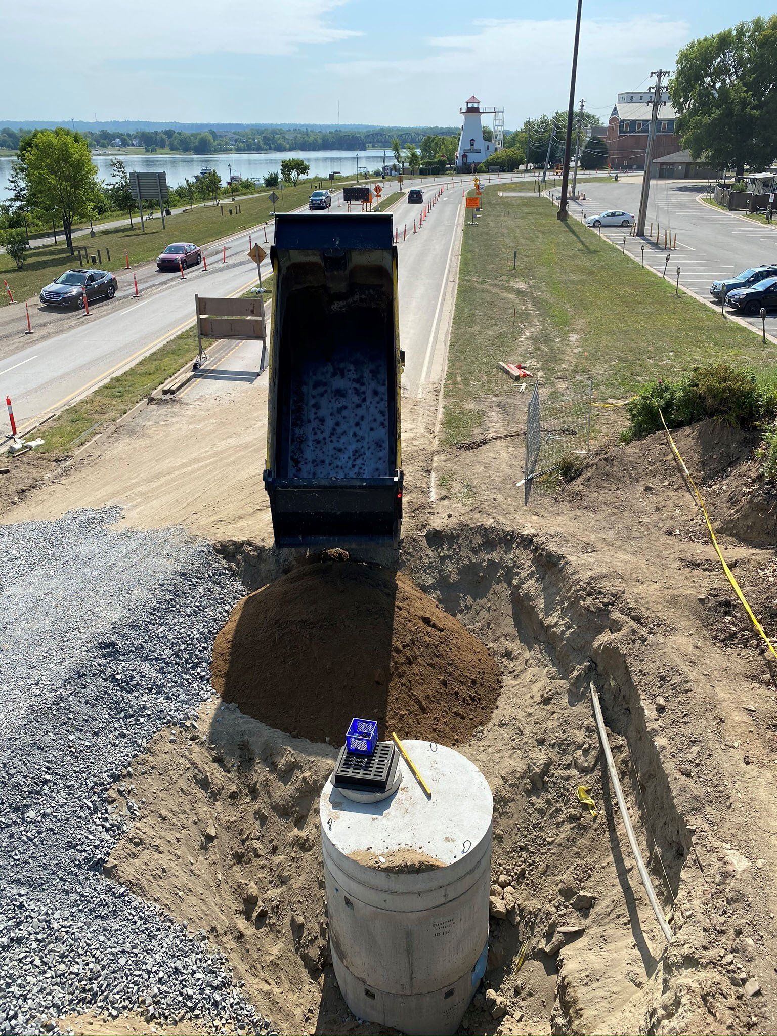 A dump truck is dumping dirt into a hole in the ground.