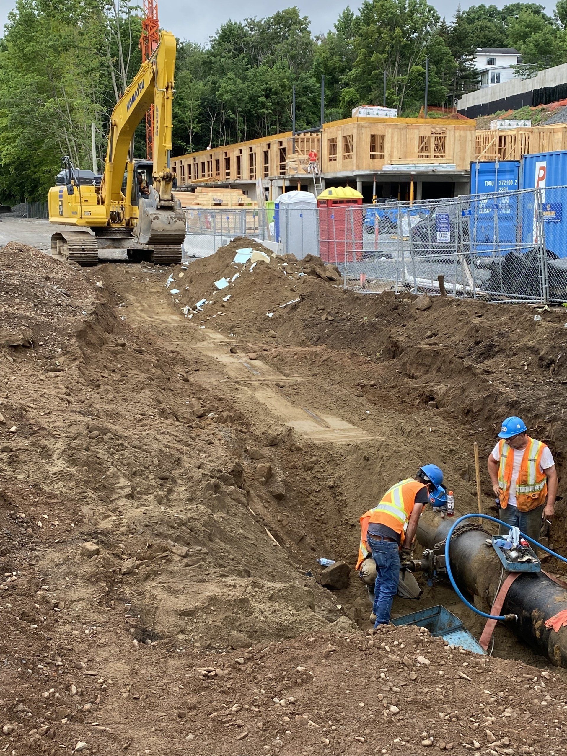 A group of construction workers are working on a pipe in the dirt.