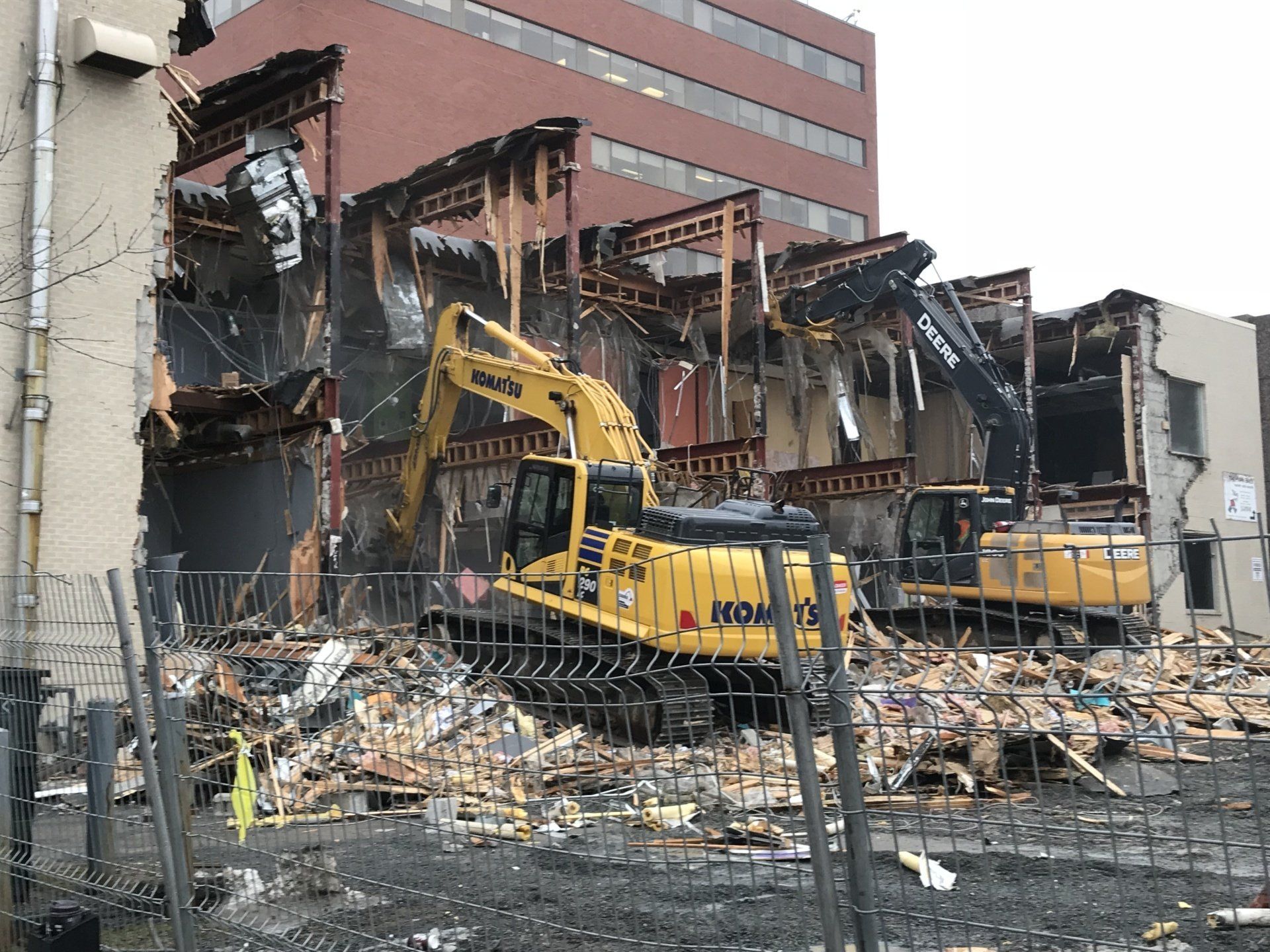 A large yellow excavator is demolishing a building.