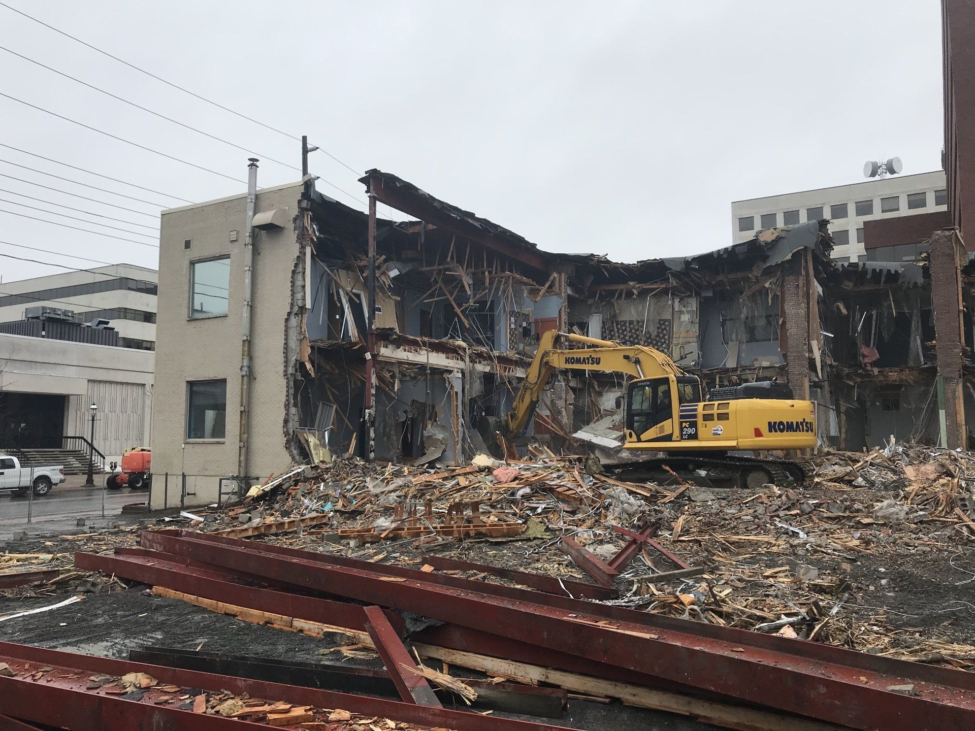 A large yellow excavator is demolishing a building.