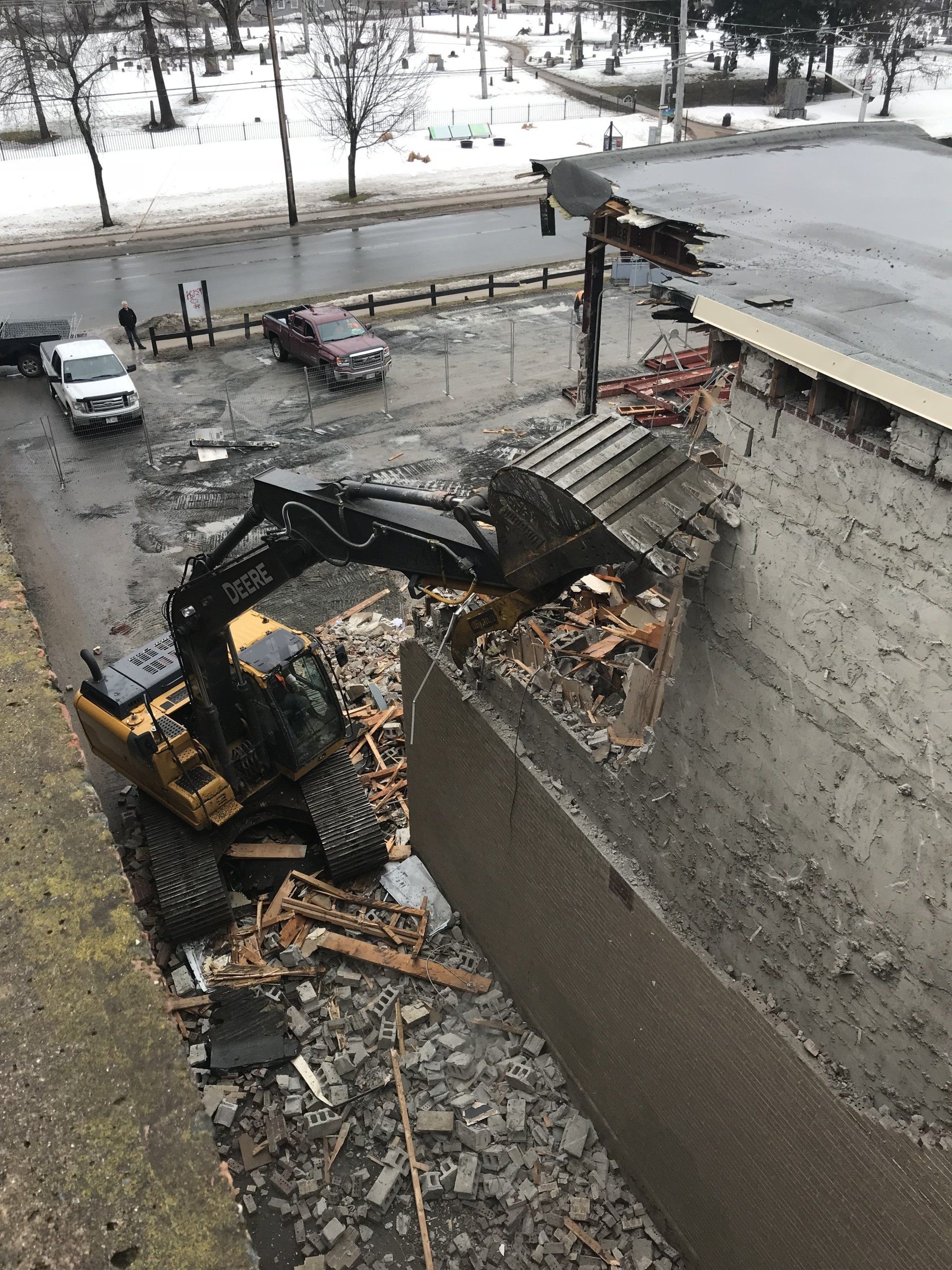 A bulldozer is demolishing a building on a snowy day.