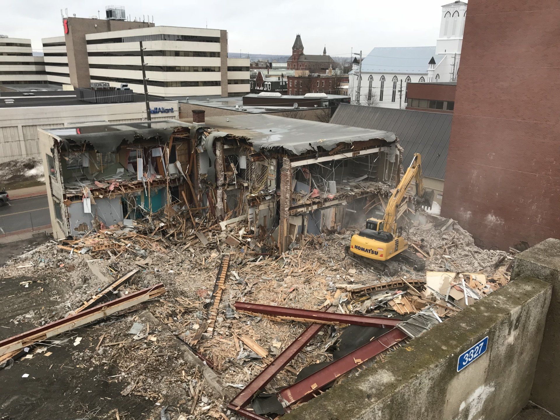 A yellow excavator is demolishing a building in a city.