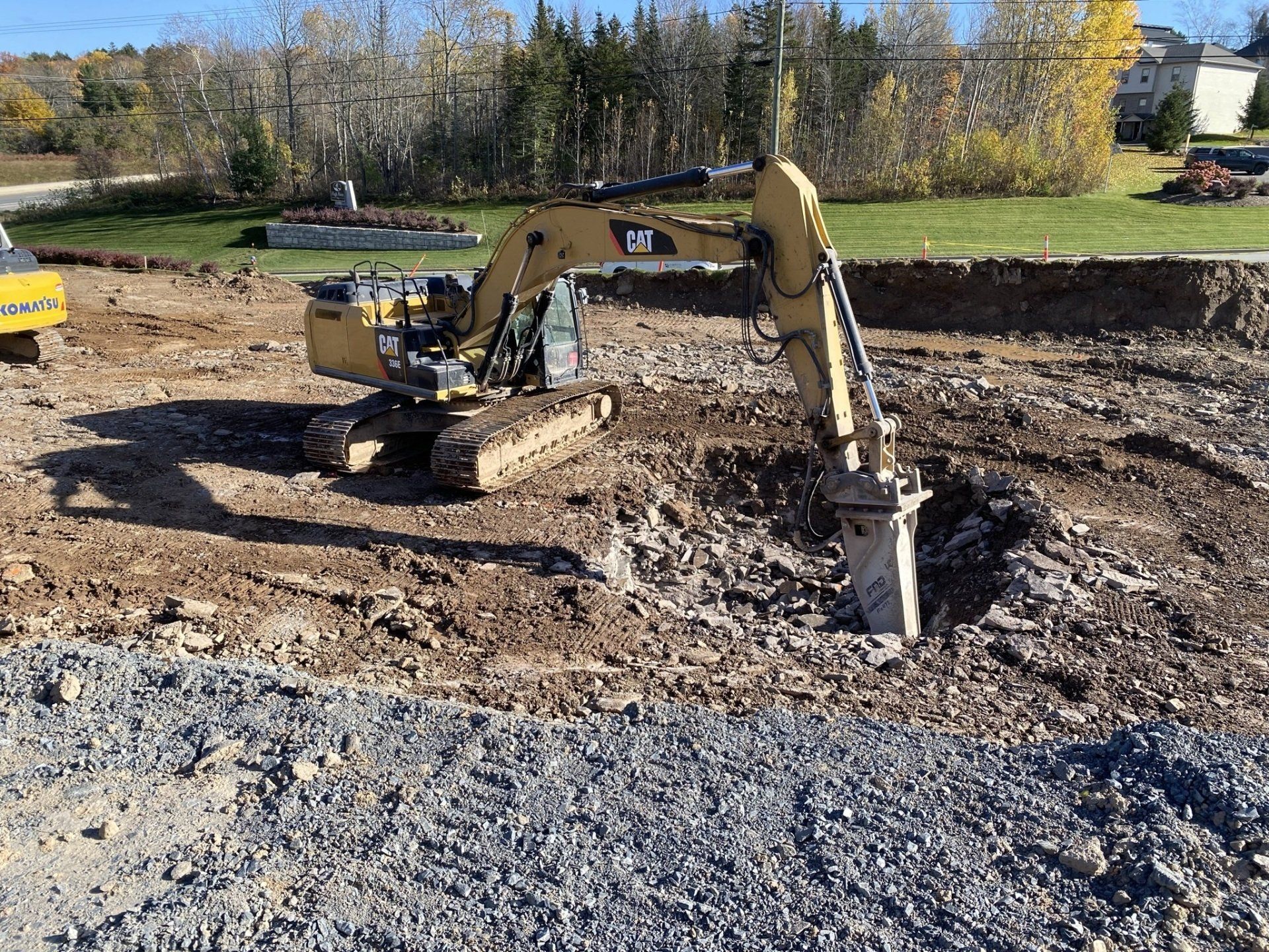 A yellow excavator is digging a hole in a dirt field.