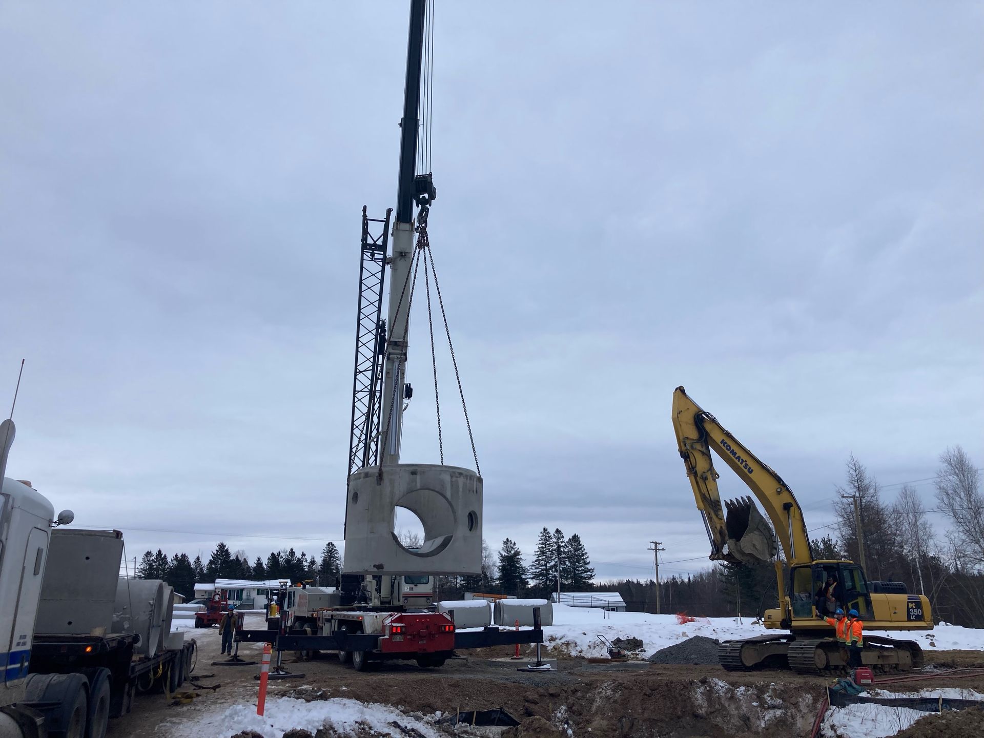 A crane is lifting a large piece of concrete in a snowy field.