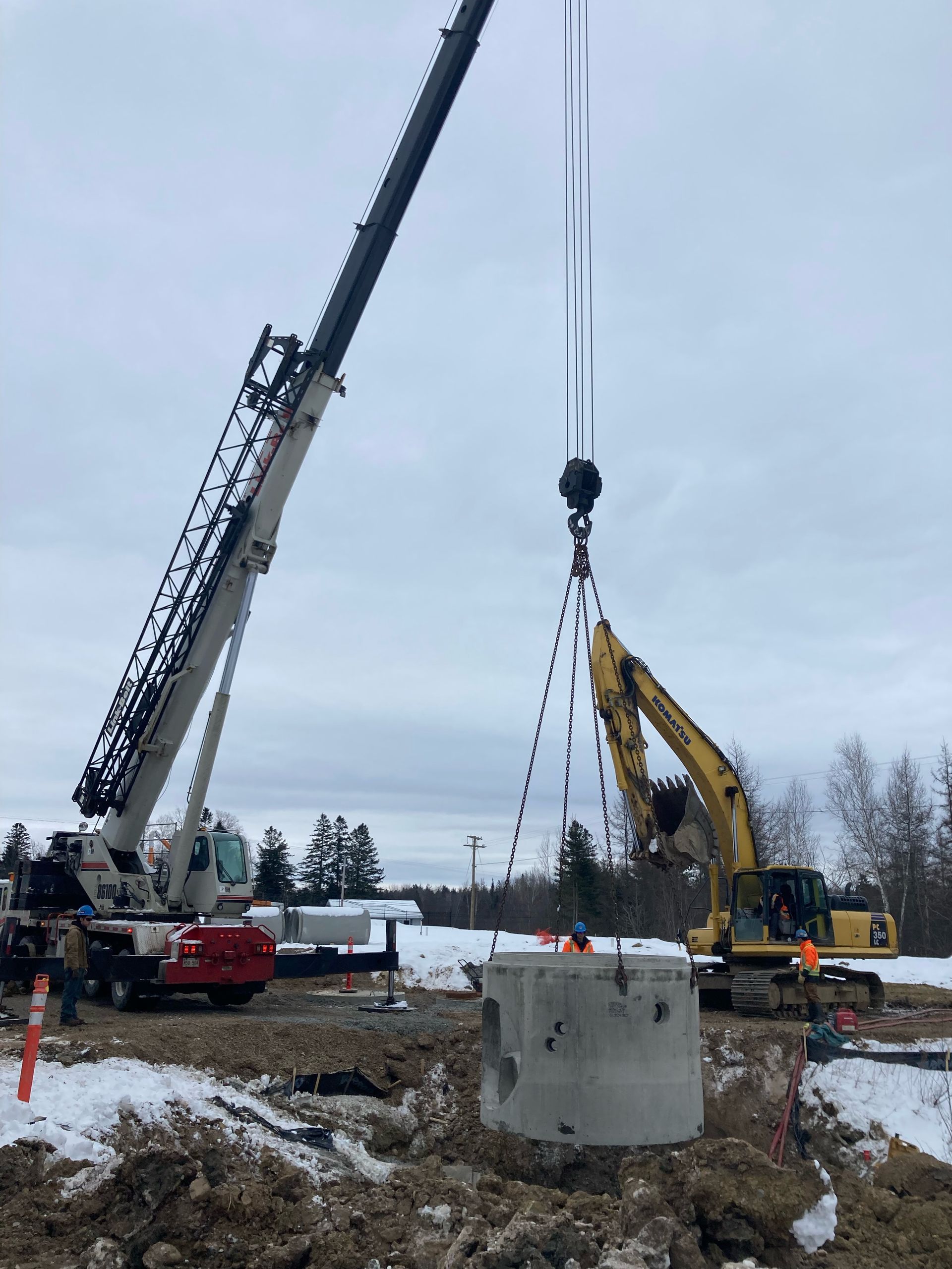 A crane is lifting a large concrete block in a construction site.