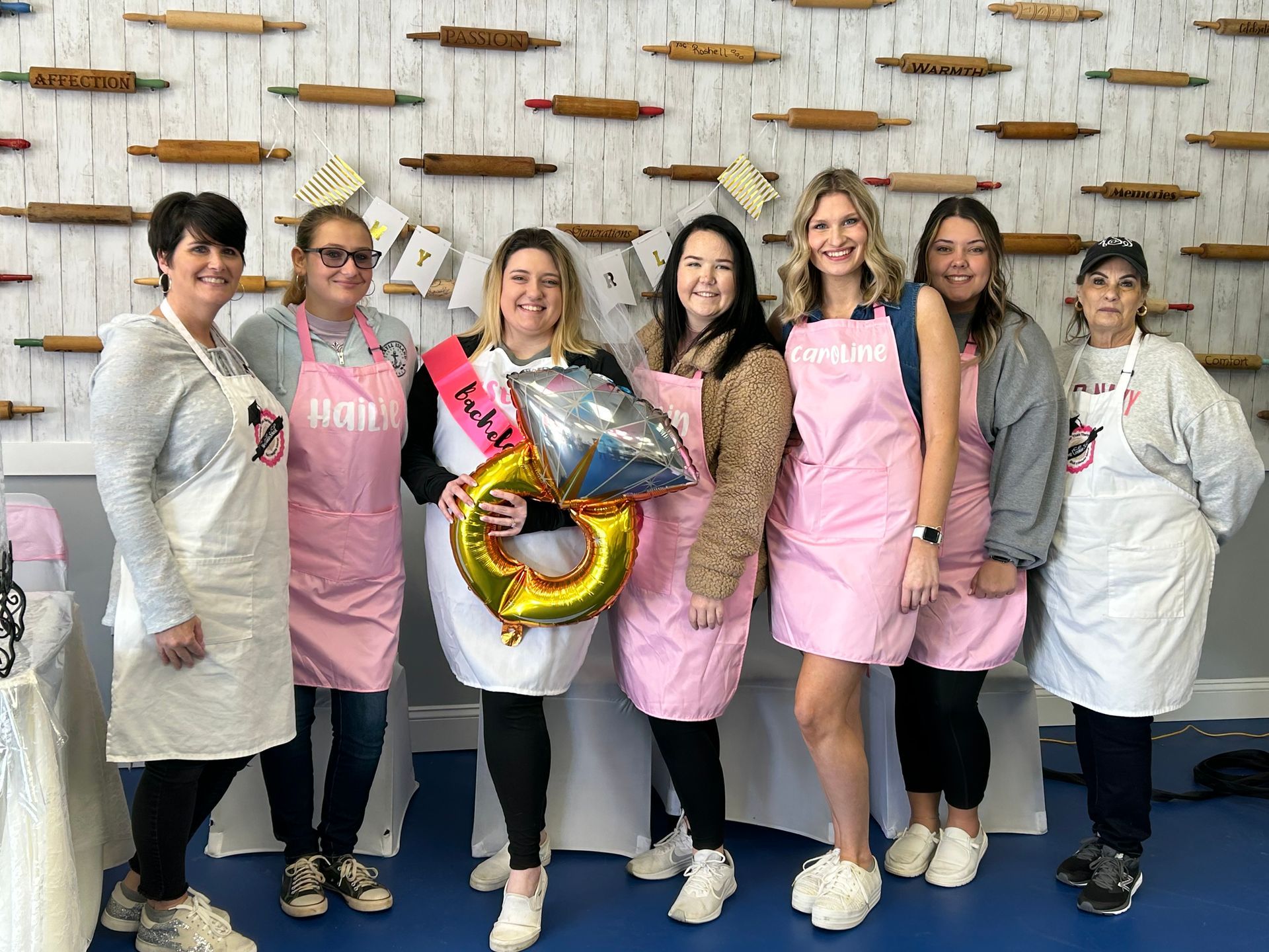 Seven women in aprons pose for a photo with a