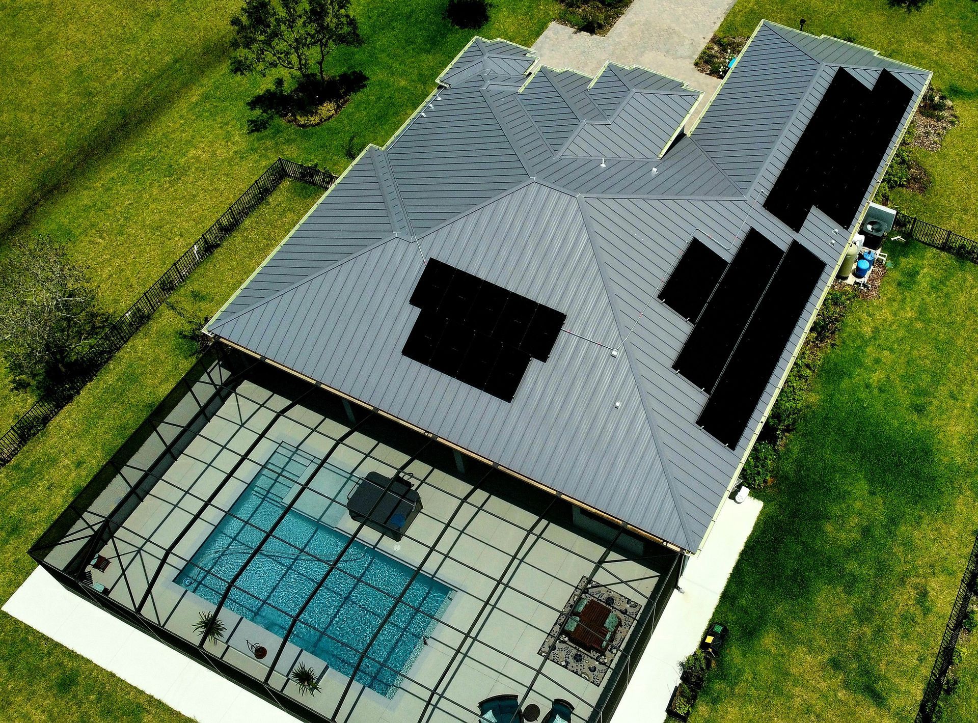 An aerial view of a house with a pool and solar panels on the roof.