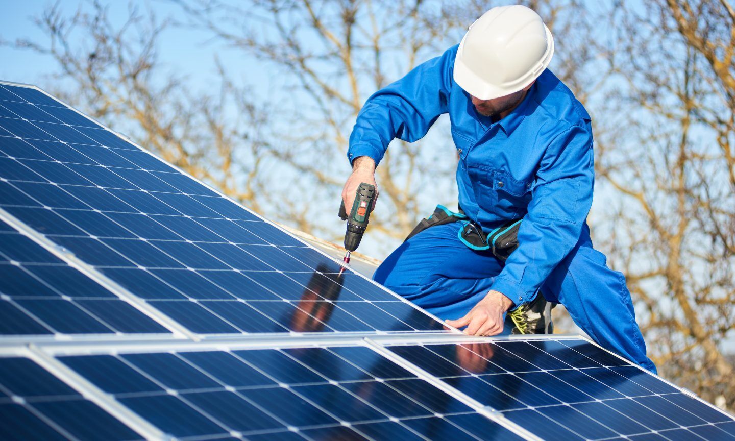 Worker installing solar panel, showcasing solar power on roof, solar energy cost, and best solar energy solutions.