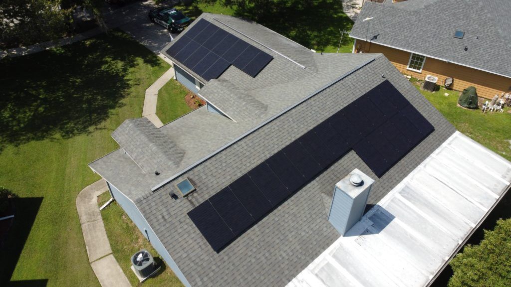An aerial view of a house with solar panels on the roof.