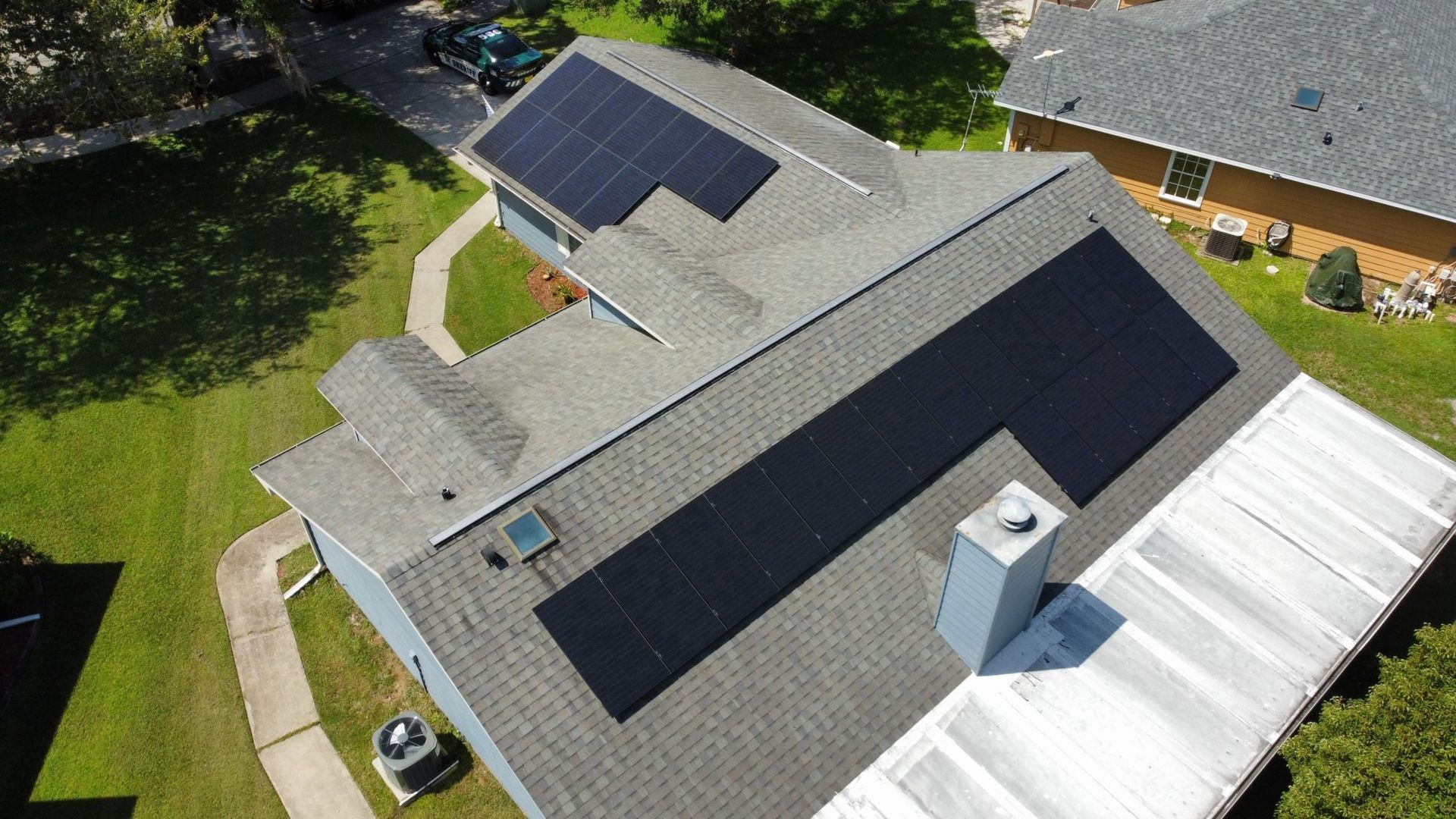 An aerial view of a house with solar panels on the roof.
