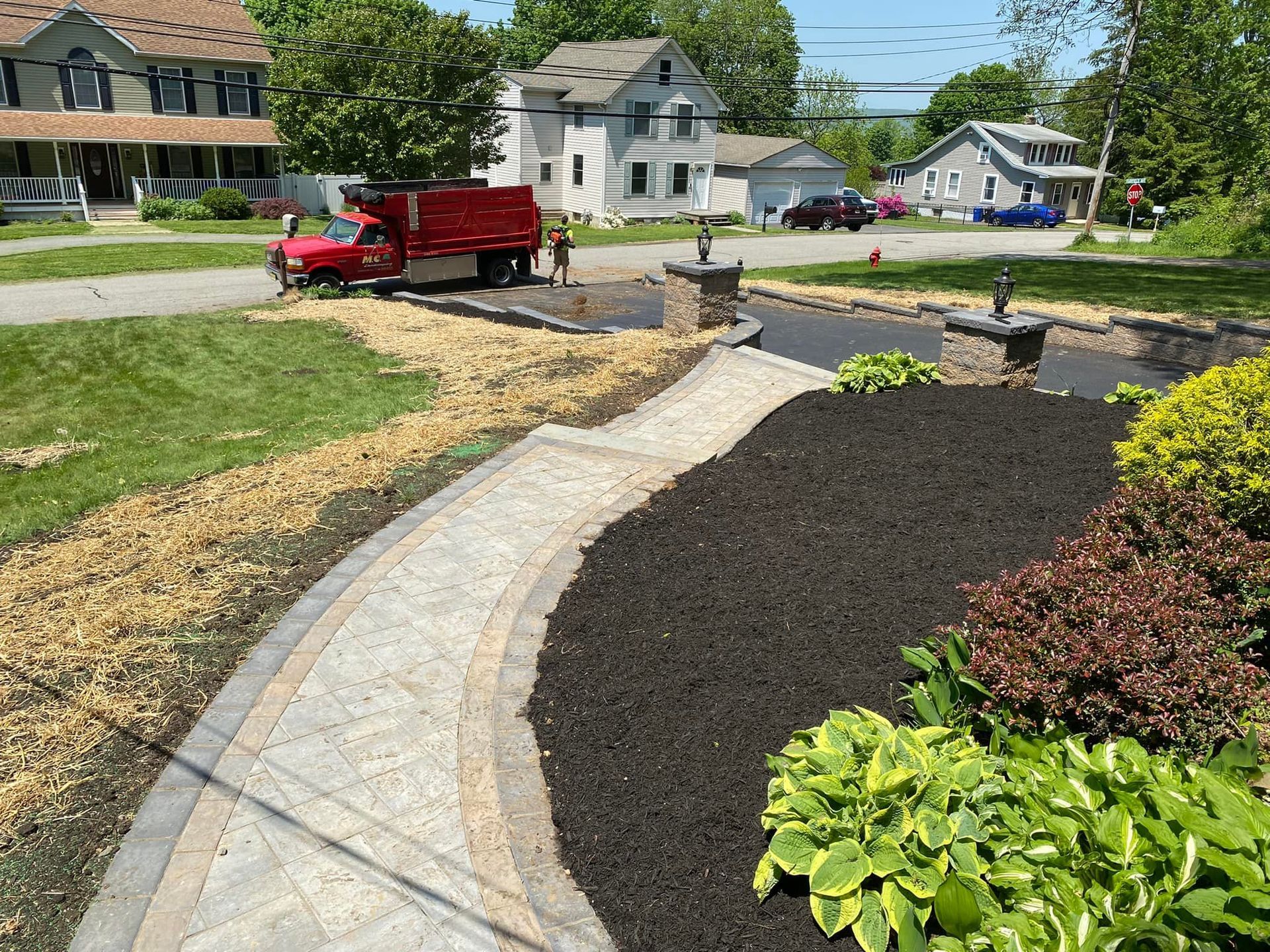 A red truck is parked on the side of the road next to a walkway.