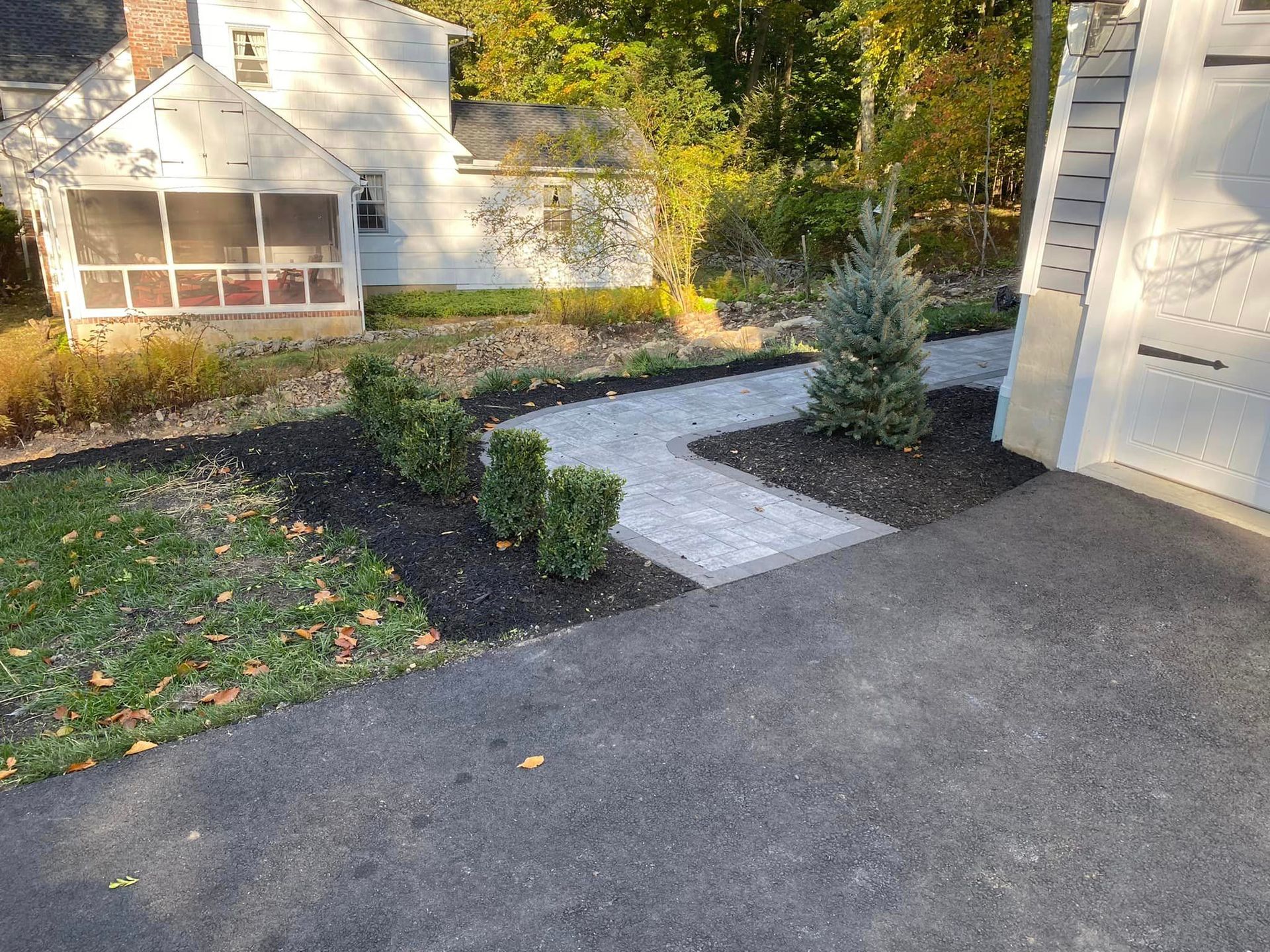 A walkway leading to a house with a screened in porch.