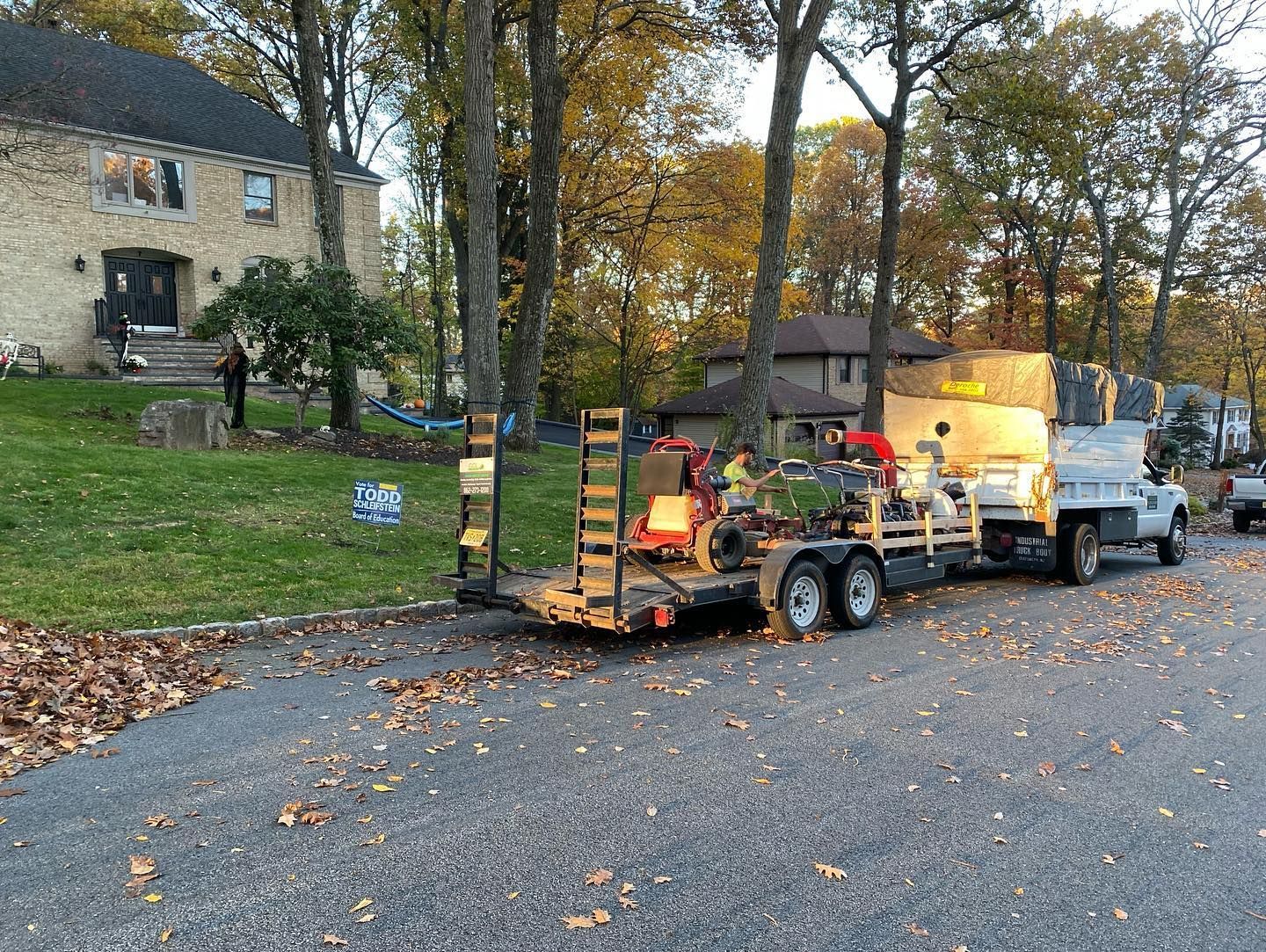 A truck with a trailer attached to it is parked in front of a house.